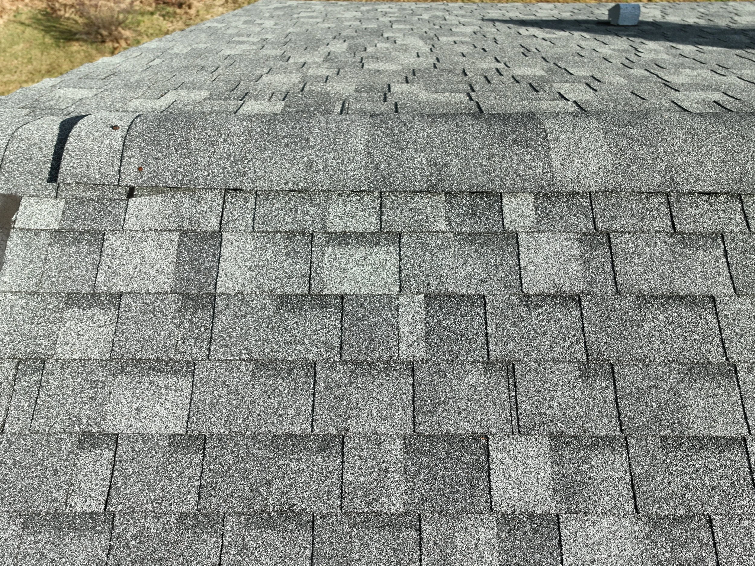 Close-up view of a gray asphalt shingle roof with a small section of the gutter visible at the top.