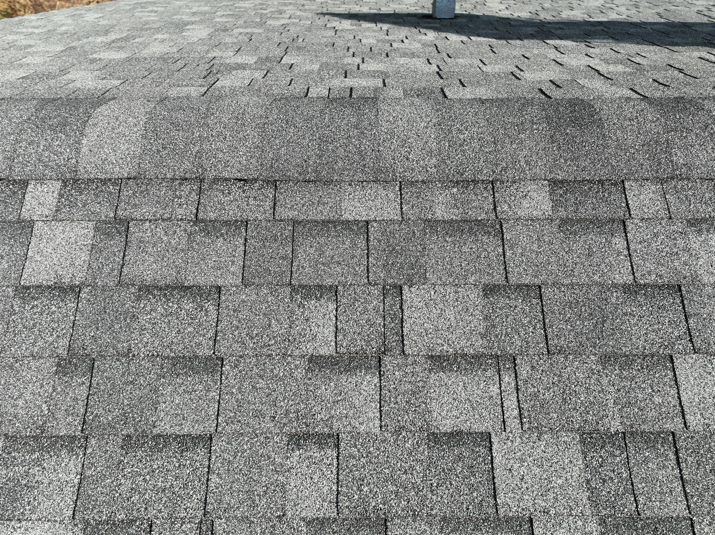 Close-up of a shingled roof with asphalt shingles in a alternating pattern.