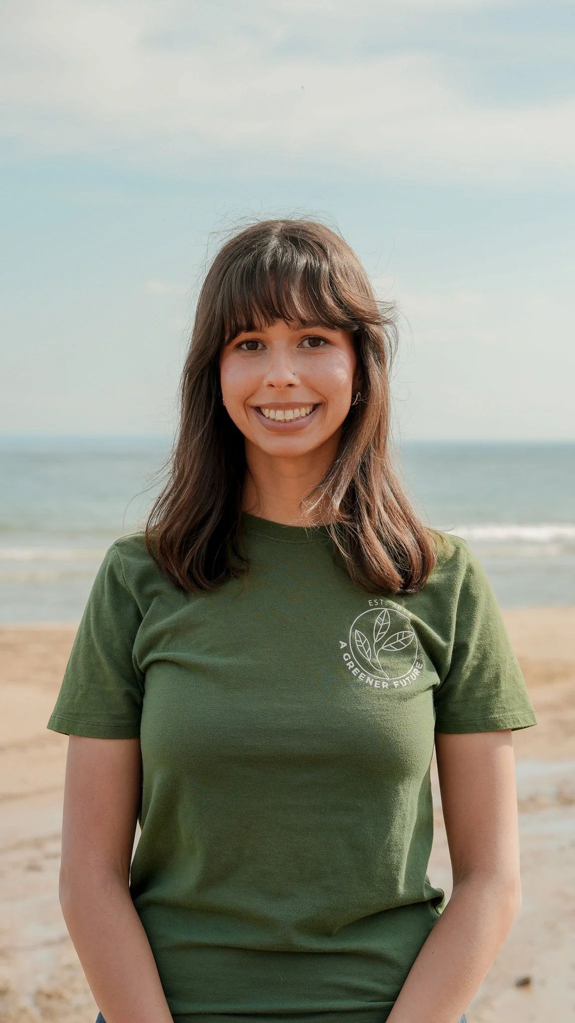 A headshot of Recia Thomas in a green shirt standing on the beach.