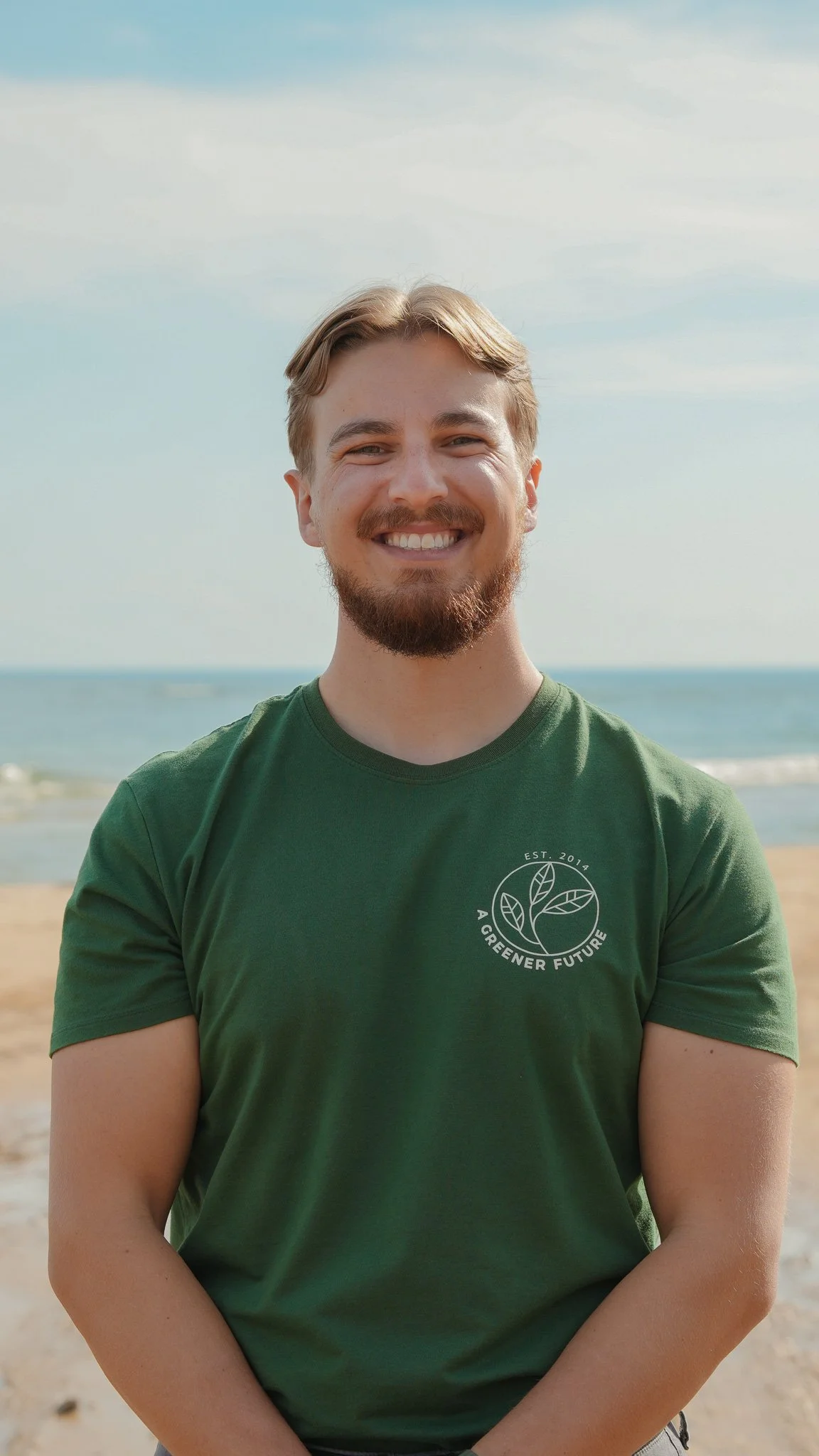Headshot of Gregory Waclawek in a green shirt standing on the beach.