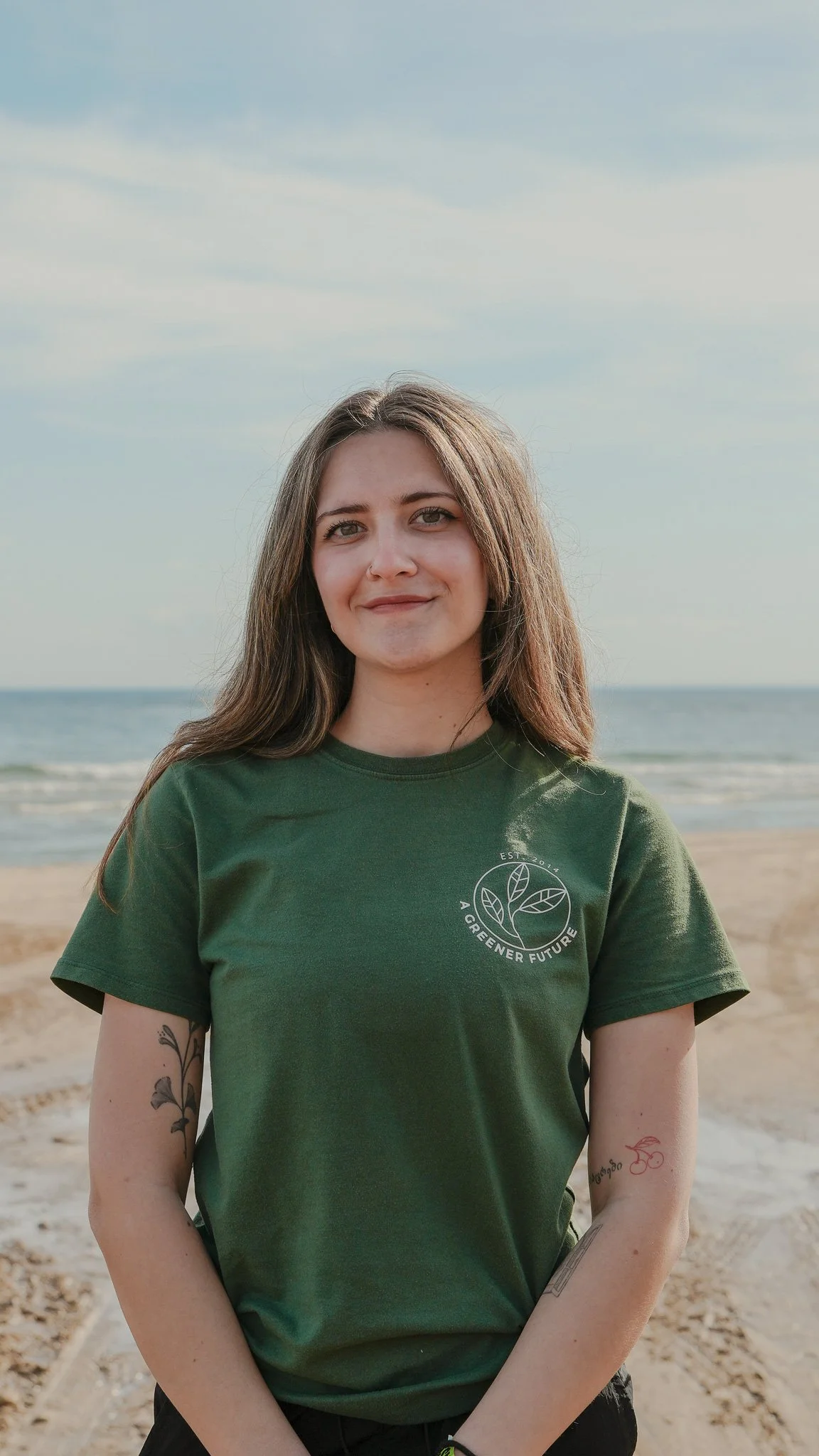 Headshot of Nino Lovell in a green t-shirt standing on the beach
