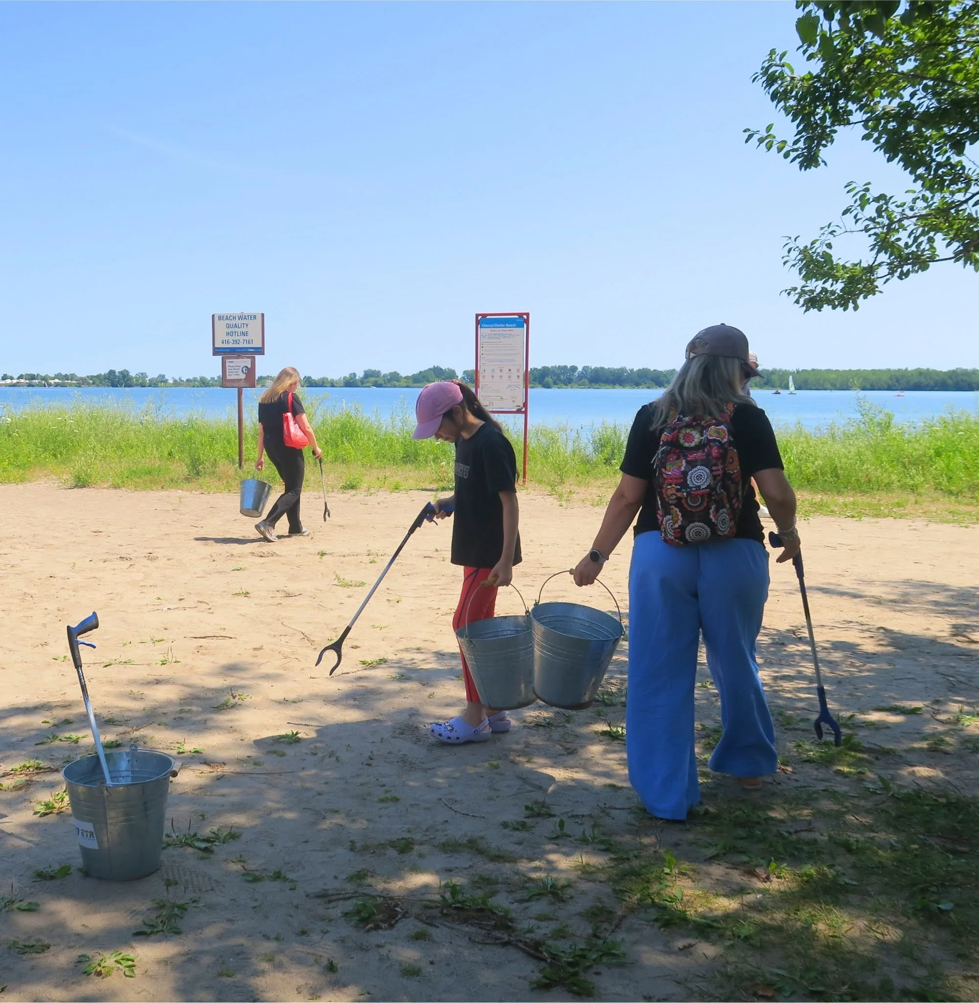 Volunteers cleaning up Cherry Beach in Toronto using litter pickers and metal buckets.