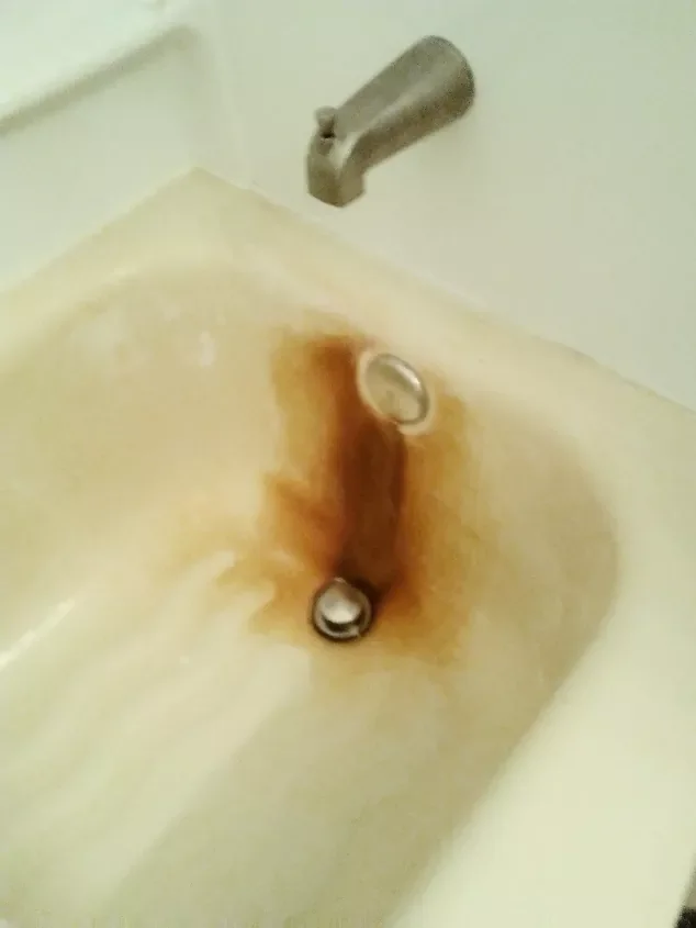 Bathroom tub with hardwater stains around the drain and faucet.