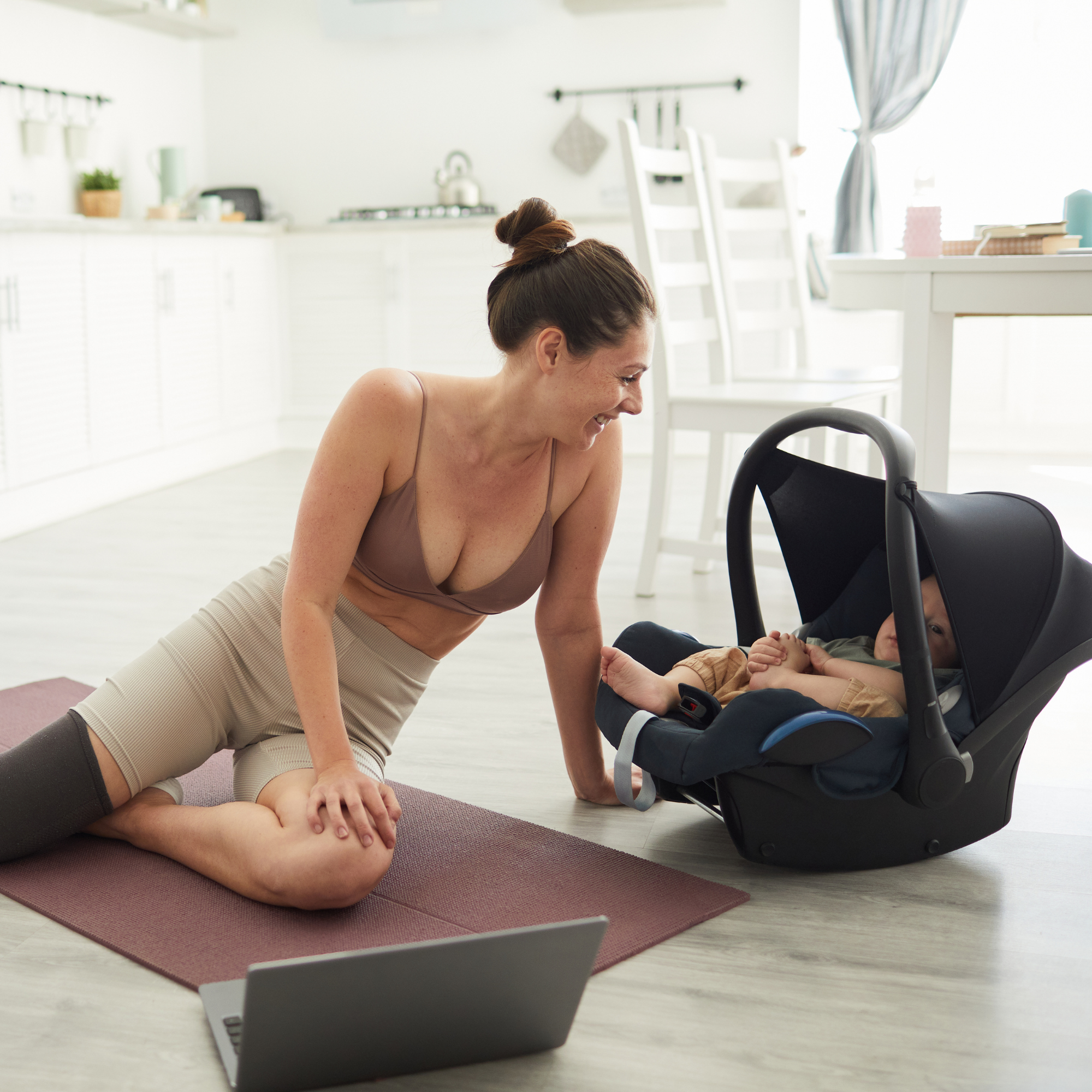 mother in walnut creek with her baby in a carrier next to her while she is doing an online coaching class in walnut creek