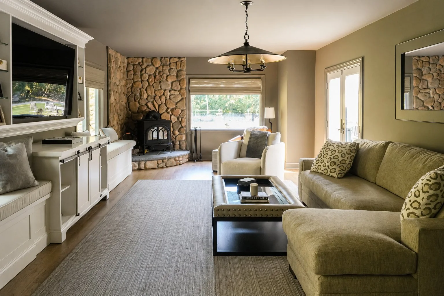 Living room with beige sofas, a stone fireplace, a large window, and a coffee table with candles, in a well-lit space.