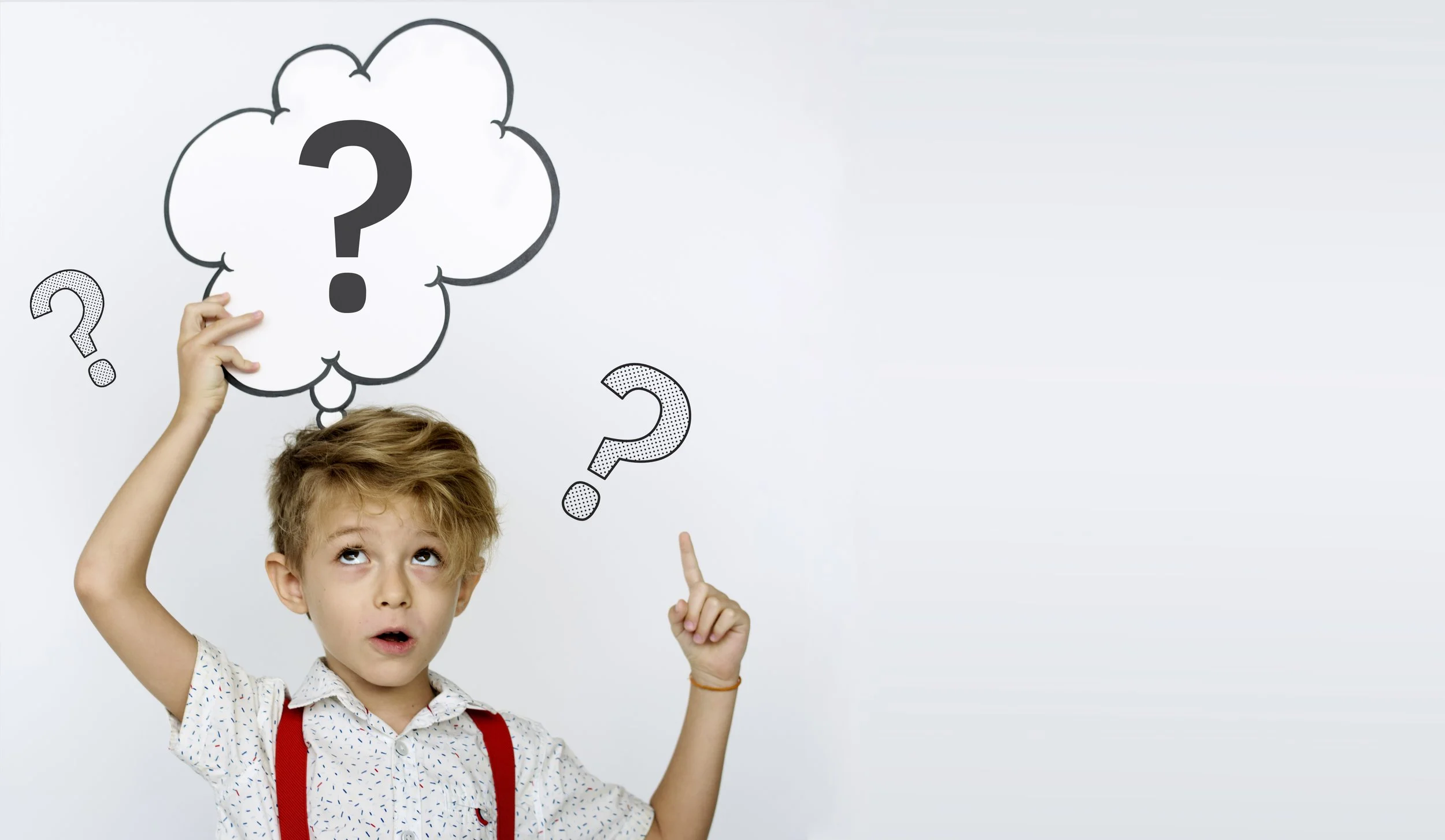 A young boy holds an imaginary question mark above his head