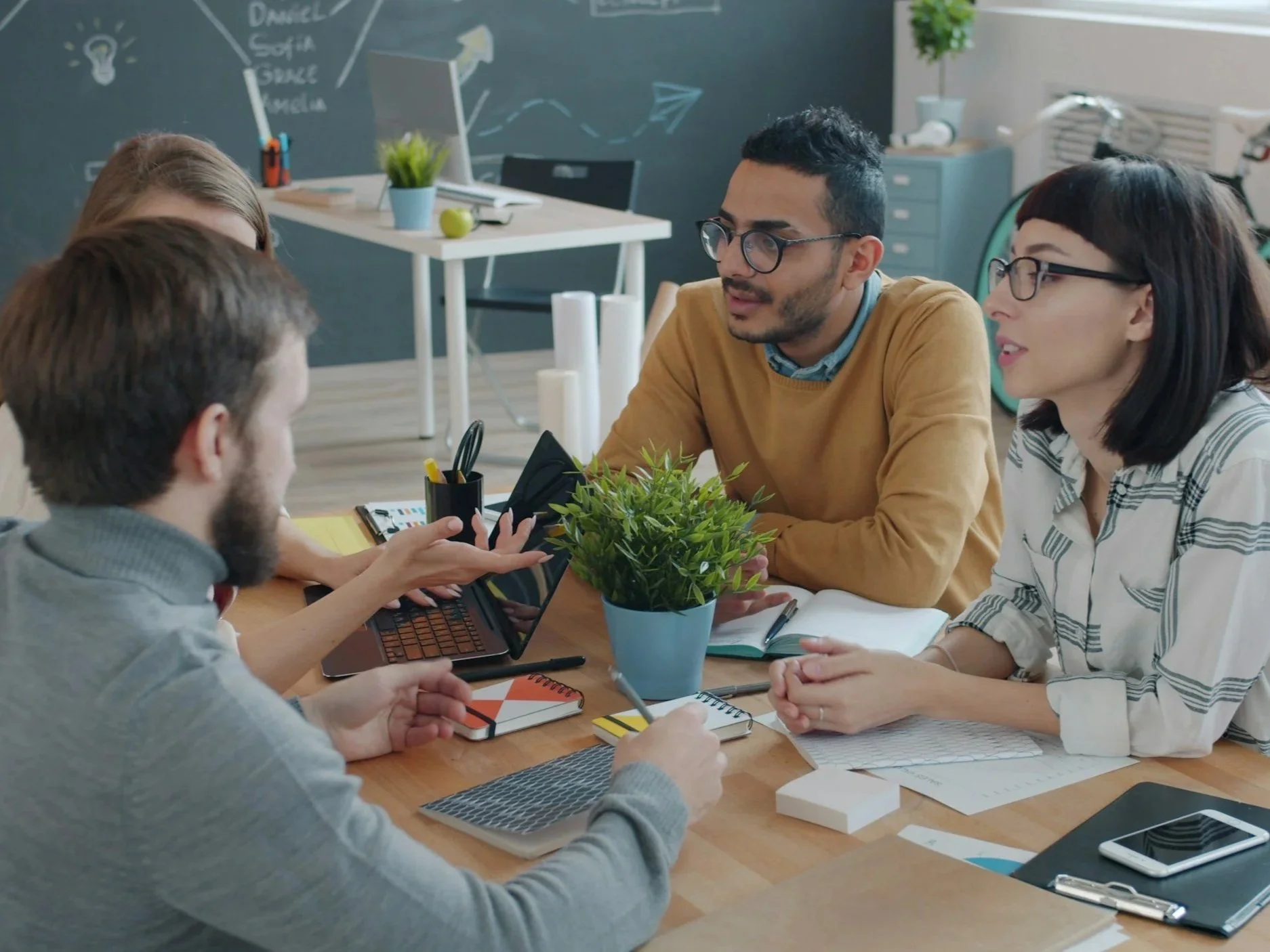 A small group of adult men and women sitting around a table and discussing