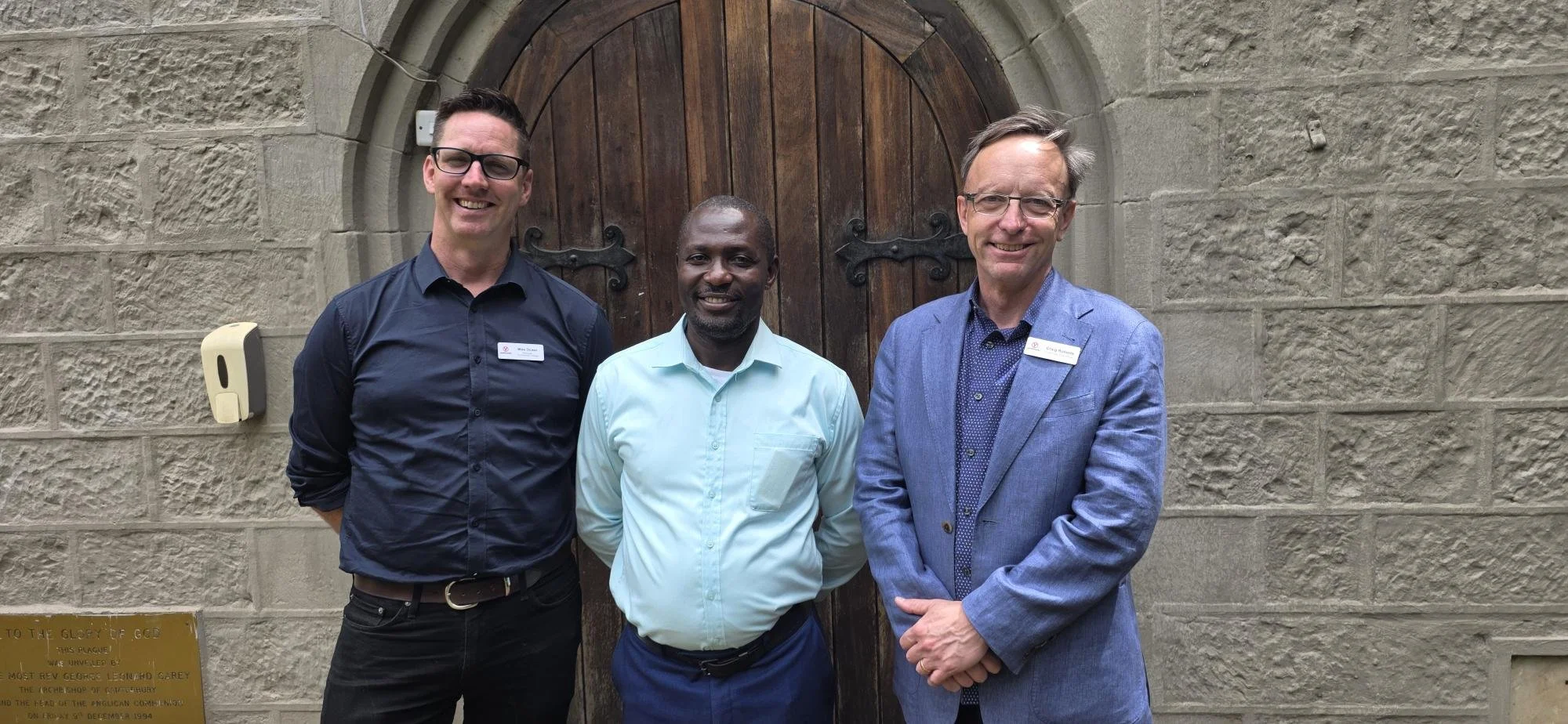 Three men standing in front of a church building