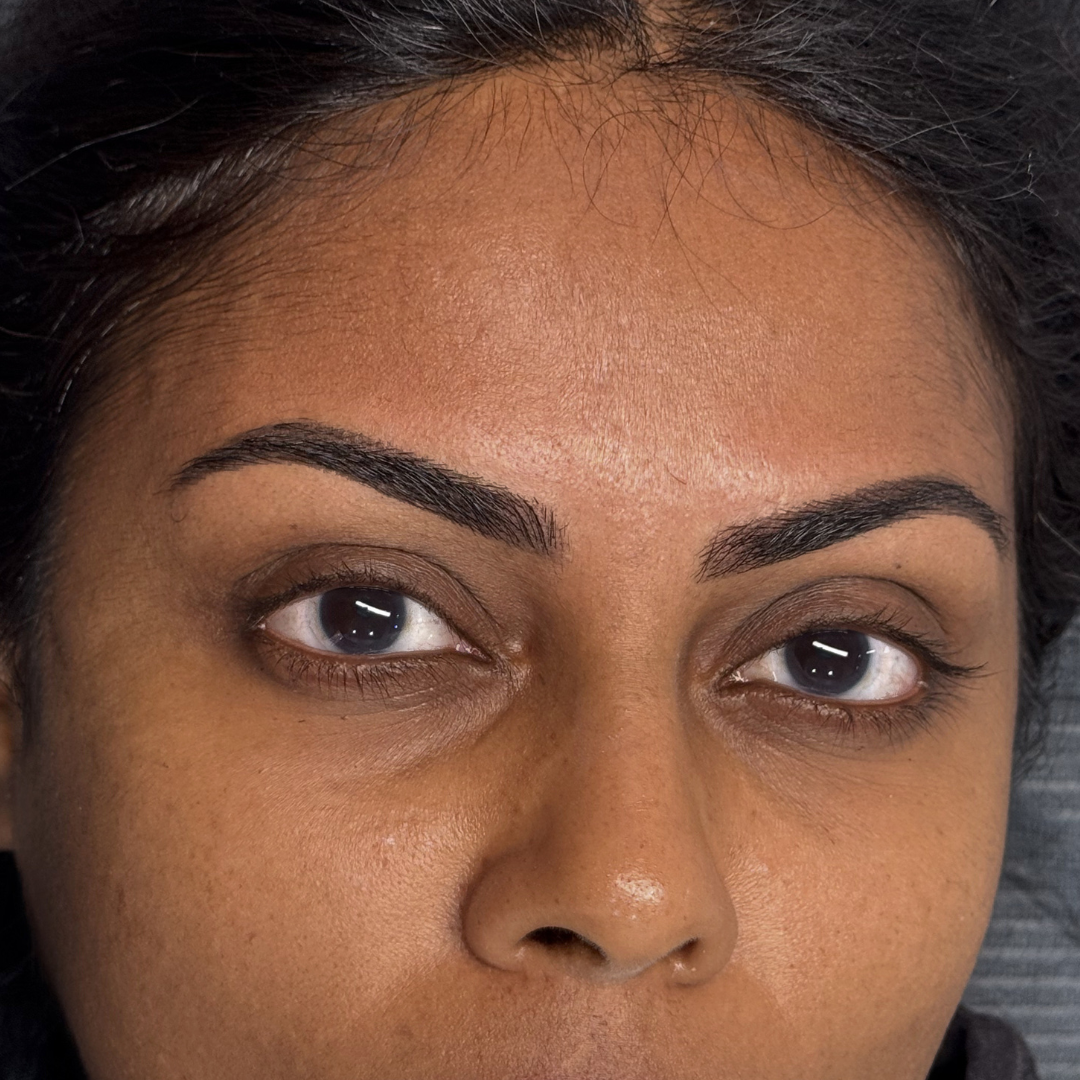 Close-up of a woman's face showing her well-groomed eyebrows, brown eyes, and smooth skin.