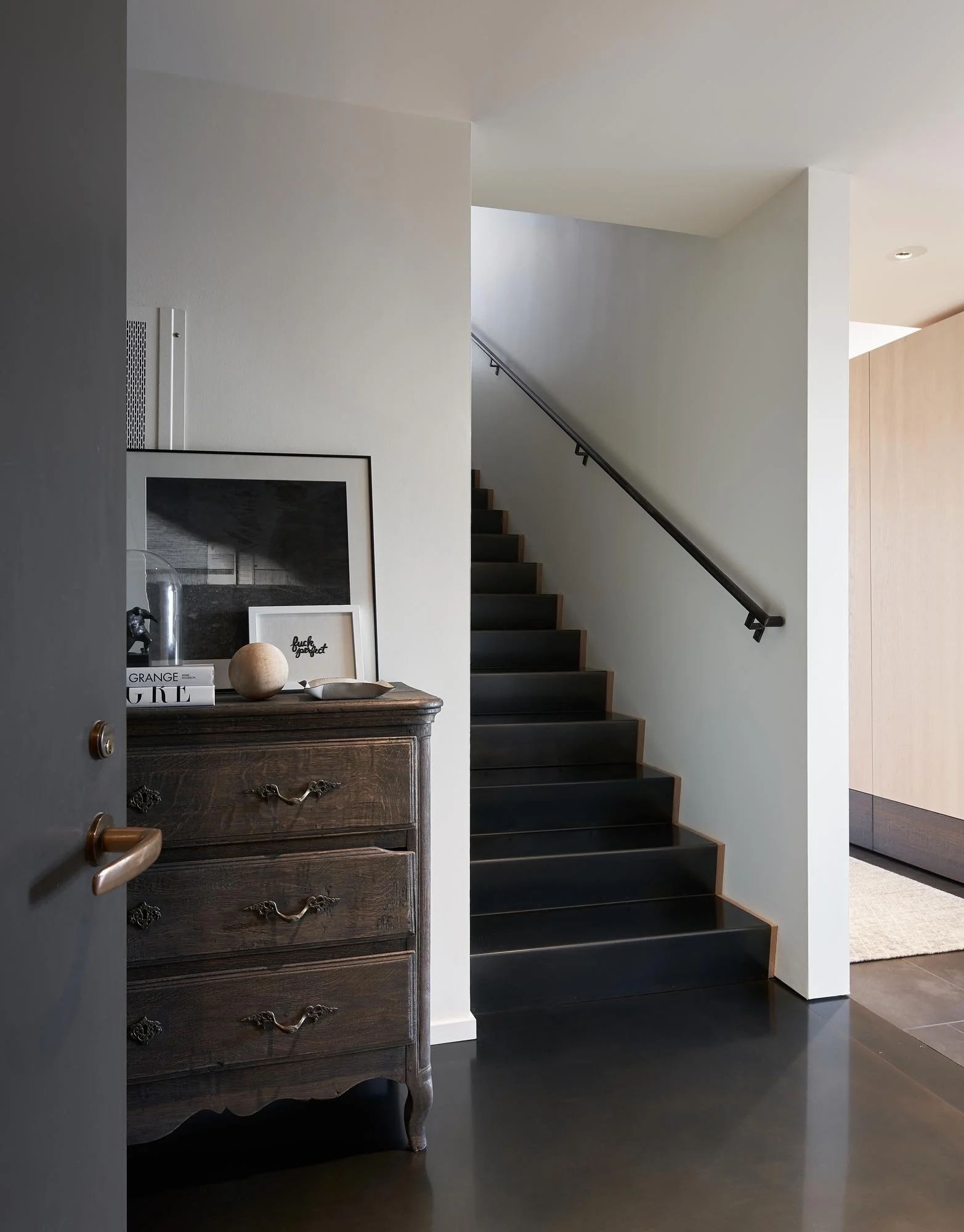 clean, modern and minimal interior entry, blackened steel floor, antique furniture, flush wall base