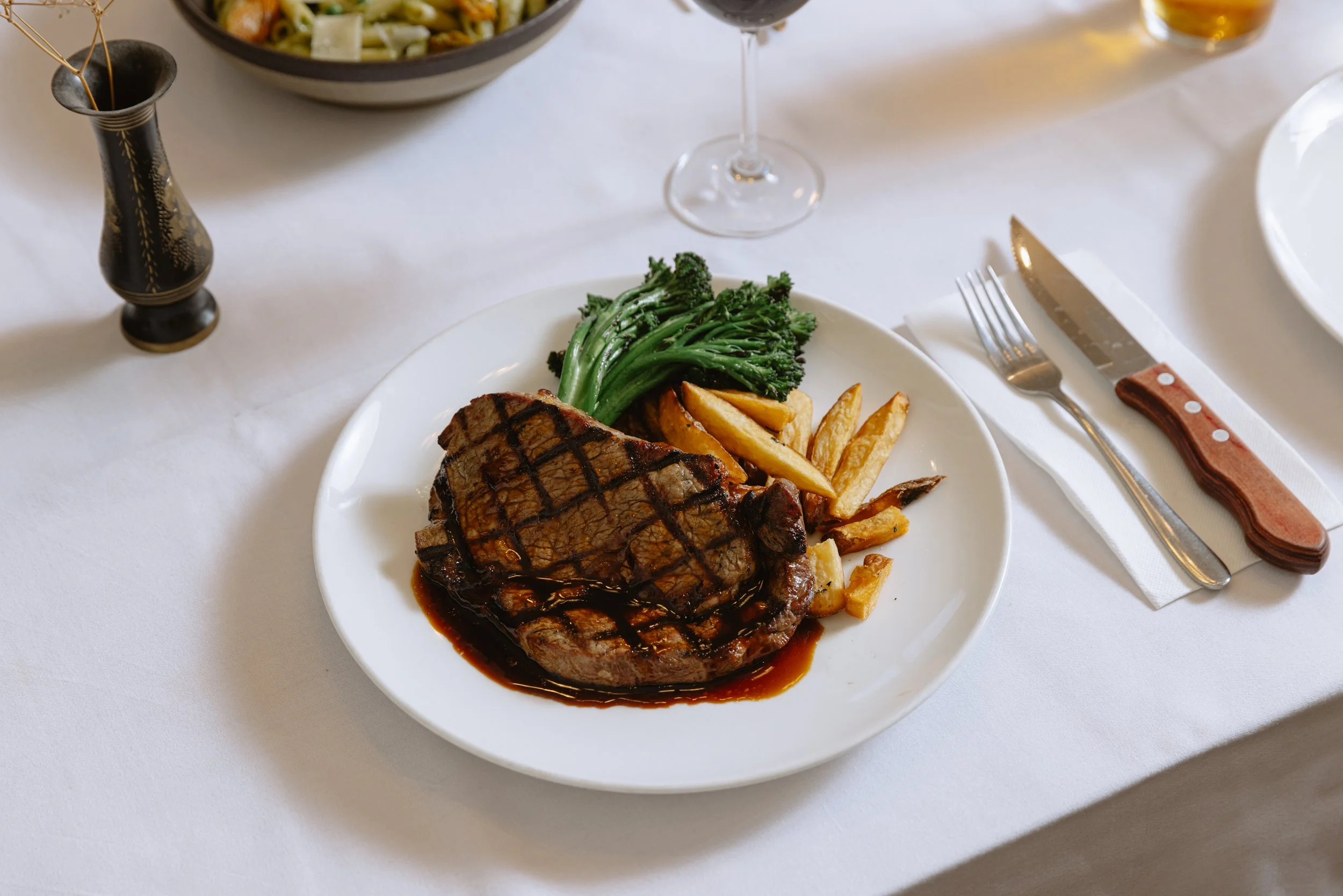 Grilled steak topped with house-made sauce, served with broccoli, roasted potatoes, and wedges at The Mint in Melbourne