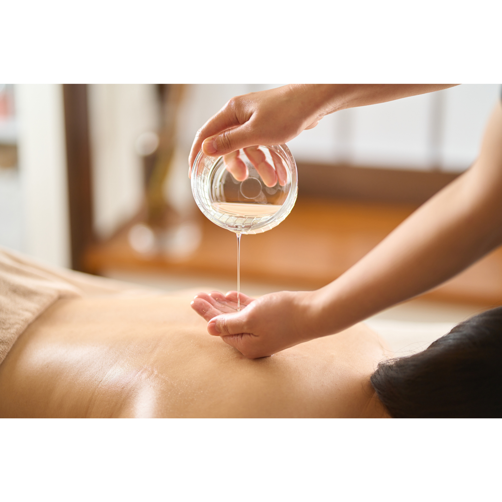 A skilled massage therapist using warmed high quality essential oils to provide a blissful relaxation massage, promoting tranquility and rejuvenation.