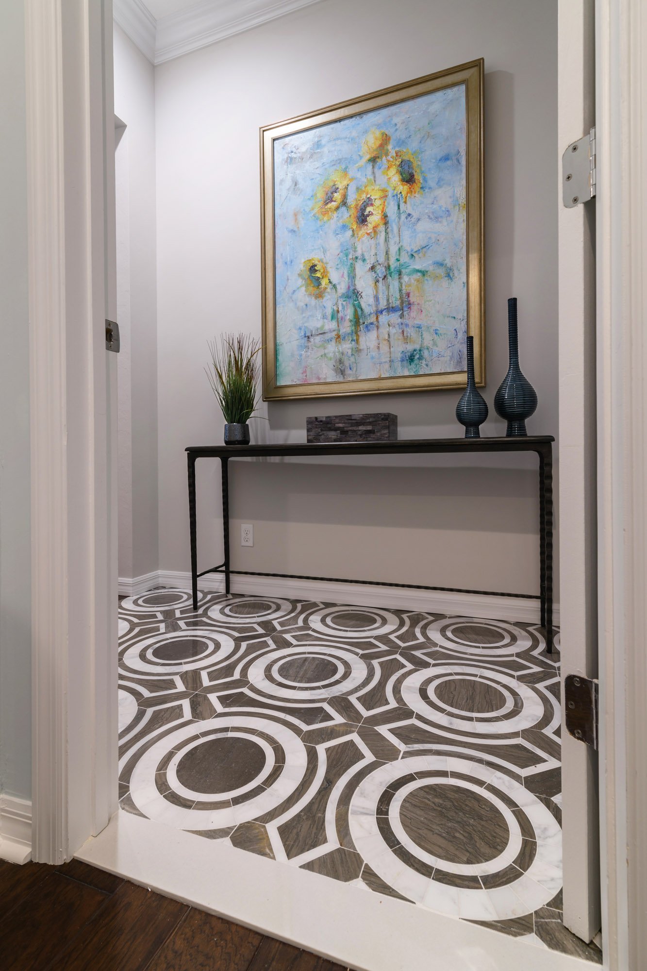 Wellington, Florida hallway with patterned tile design, console table, and sunflower oil painting.