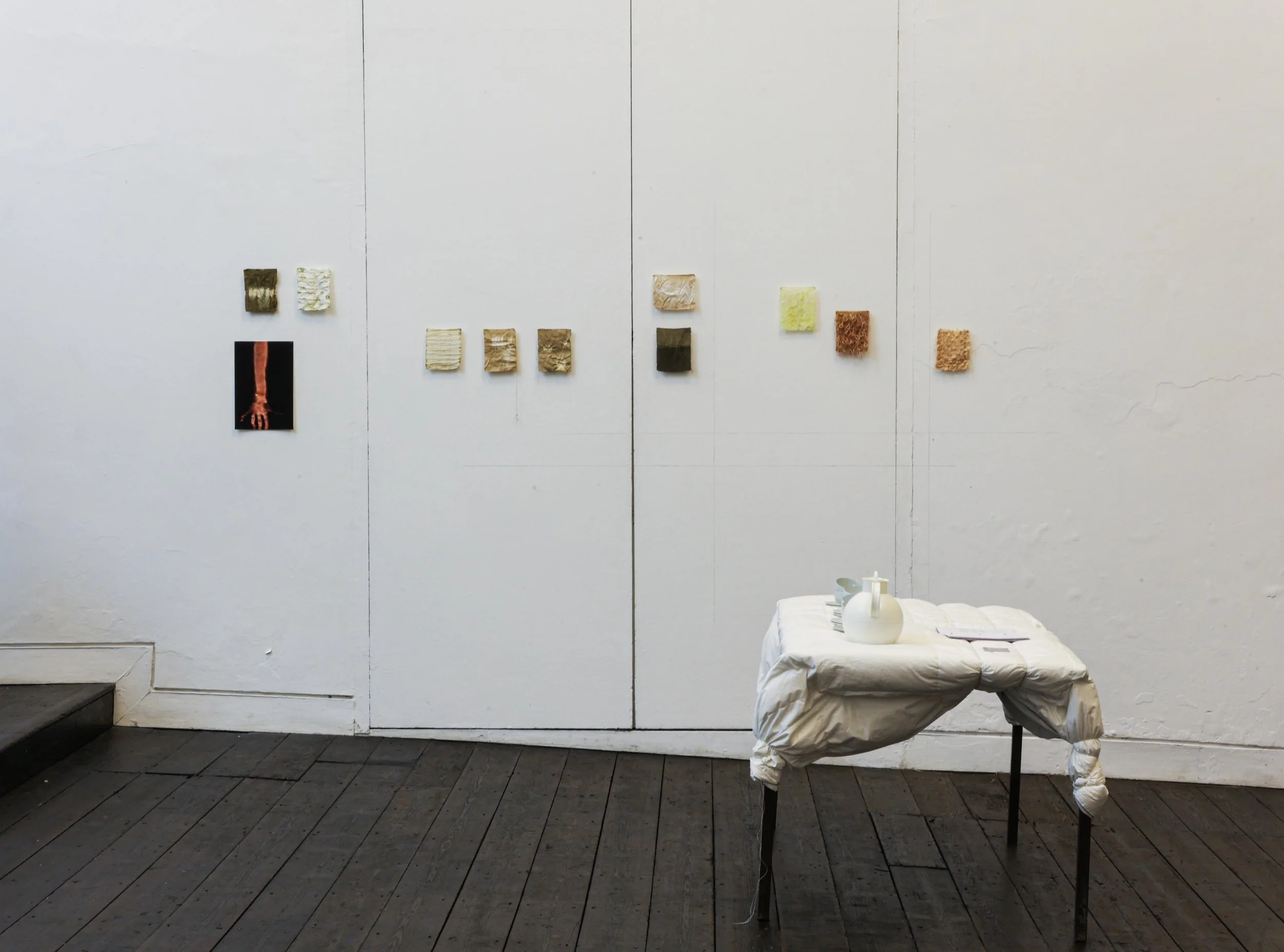 'Thin Skin, Thin Places', 2025. Installation comprising a metal table, duvet, wire and thread; silk artworks dyed with rosemary pigment; herbal tea served in ceramic cups; and a publication bound with steel. Presented as part of 'Surfaced', Beaconsfi