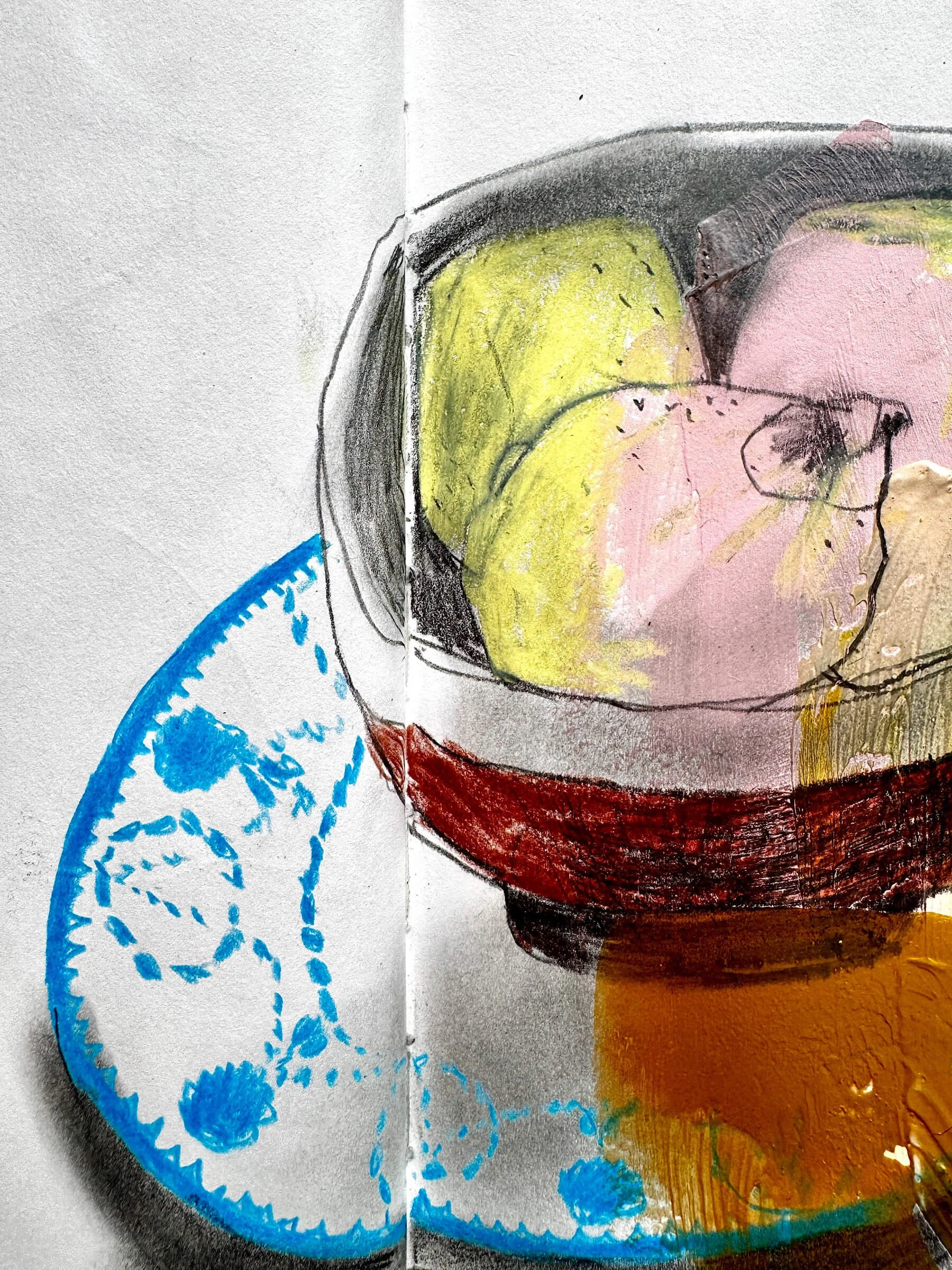A close-up of an open artist sketchbook page displaying an expressive mixed-media charcoal, pencil, and paint drawing of lemons in a ceramic bowl resting on a bright blue and white patterned saucer.