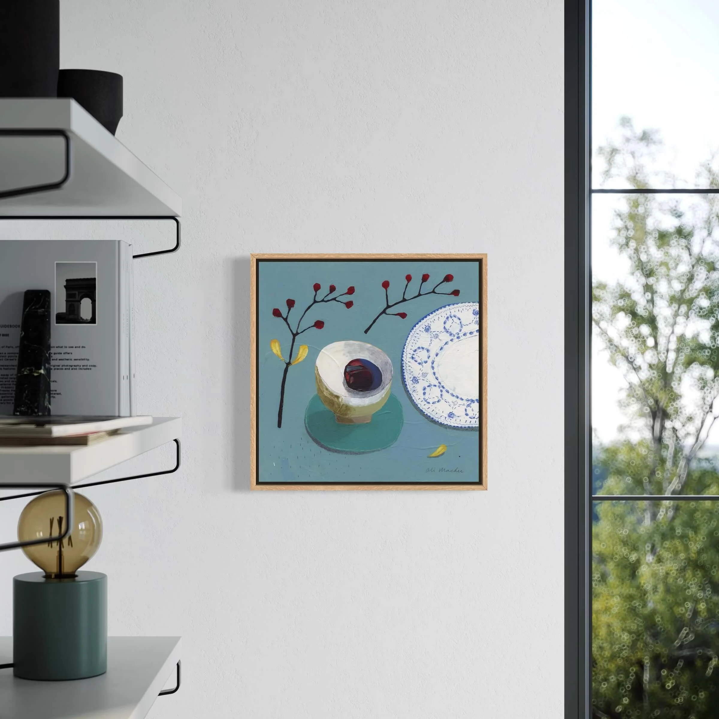 Living room interior mockup featuring blue still life art by Ali Mackie Art displayed on a light wall near a window.