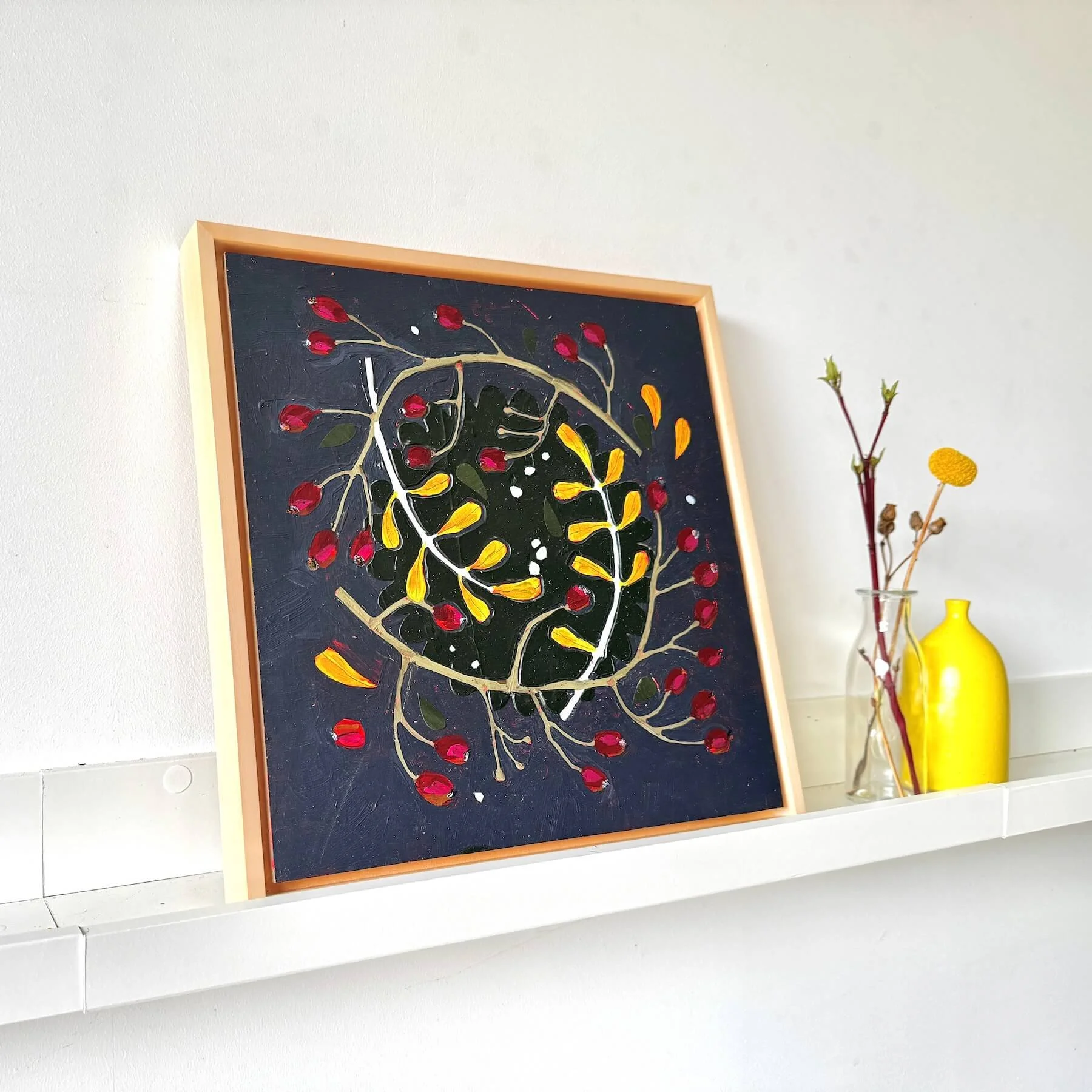 Close angled right view of the framed original painting Wilder by Ali Mackie Art resting on a white shelf display.
