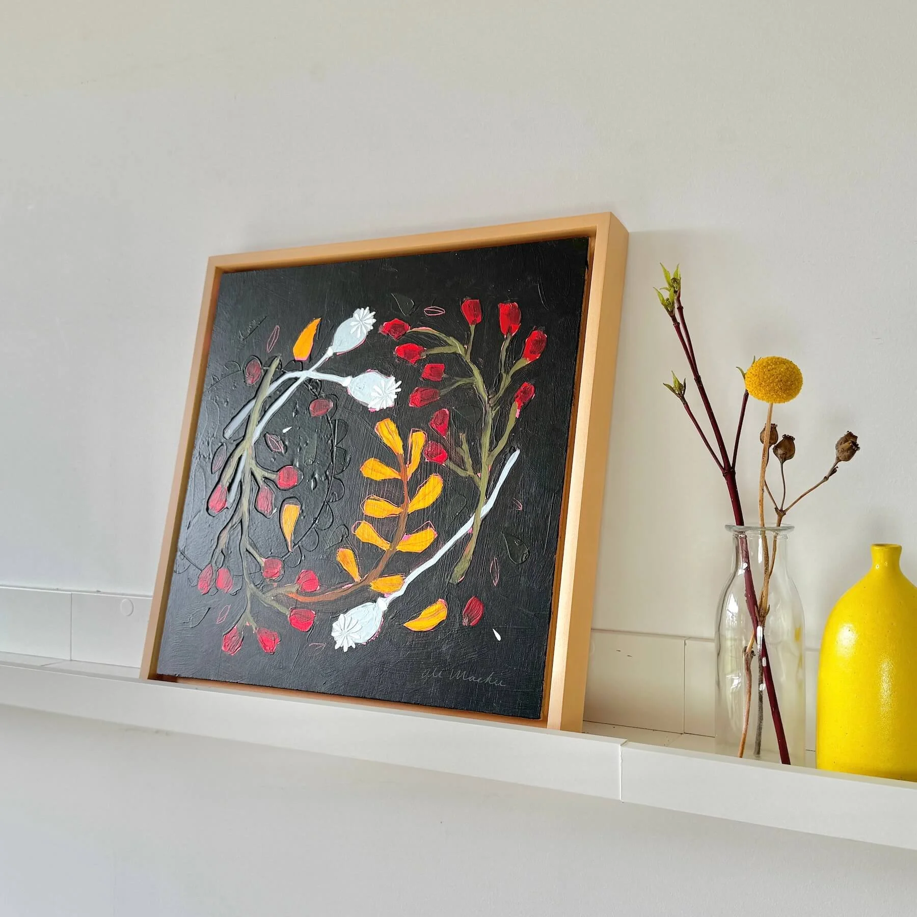 Side angle view of the framed original painting Wilda by Ali Mackie Art sitting on a shelf next to dried craspedia and a yellow ceramic vase.