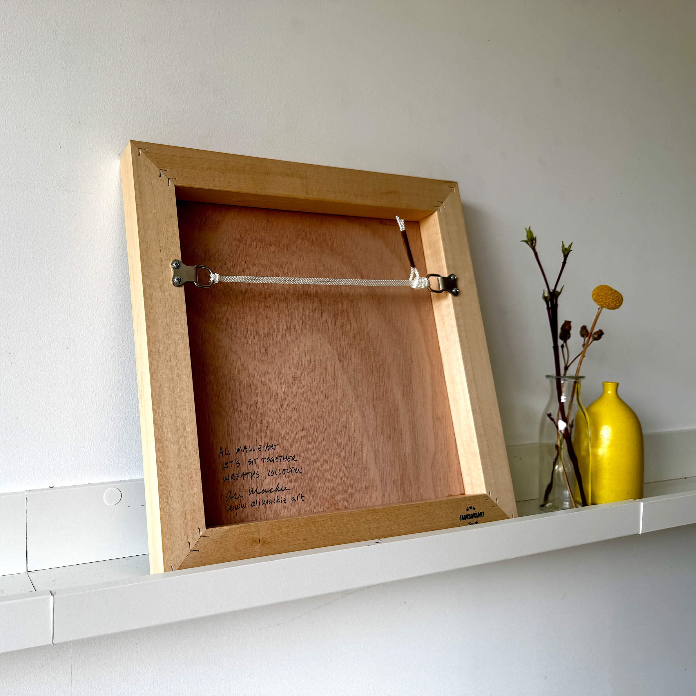 Back view of natural wood float frame for Lets Sit Together original artwork signed by artist Ali Mackie Art with hanging wire.