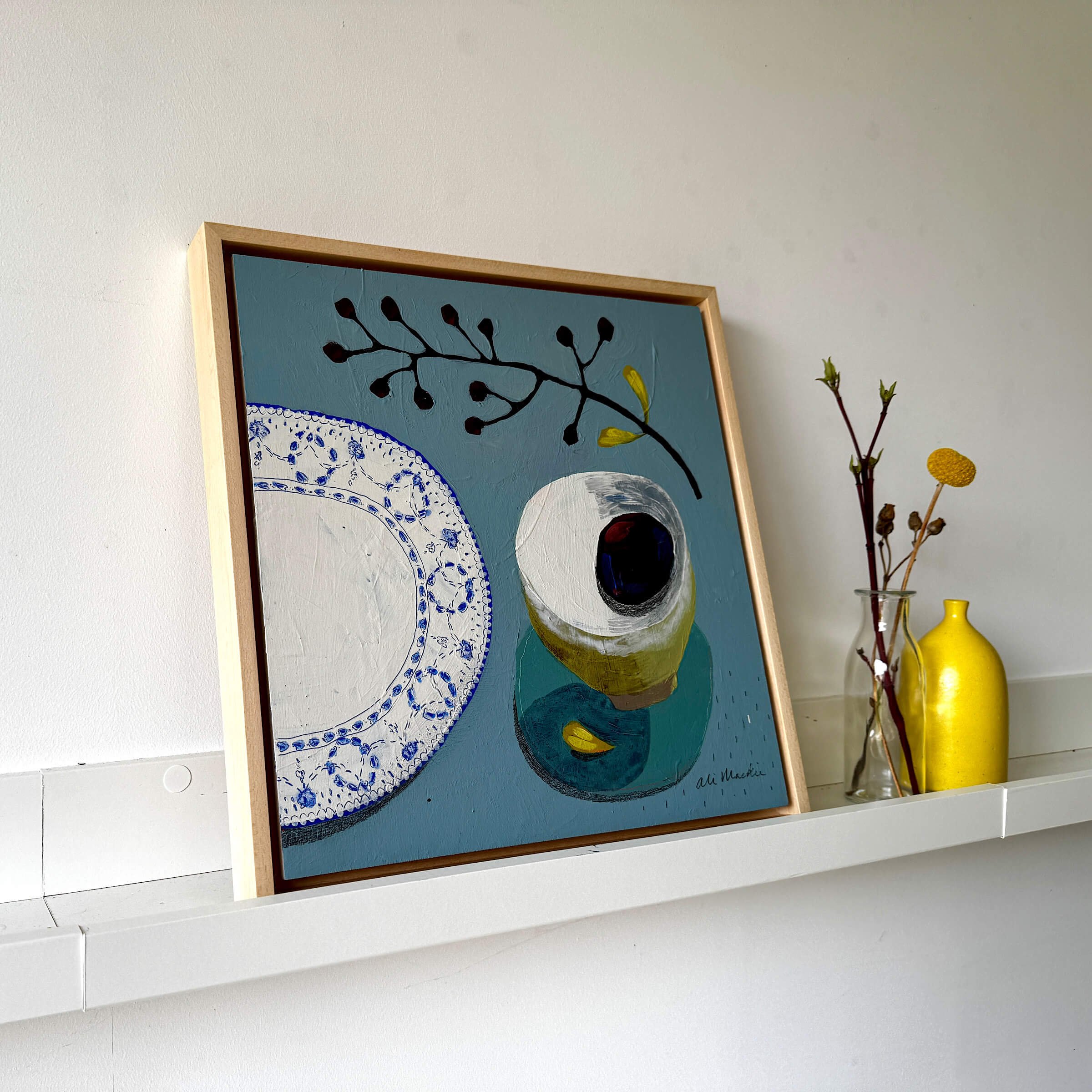 Framed still life art Lets Sit Together by Ali Mackie Art featuring a blue patterned plate, teacup, and berry branch.