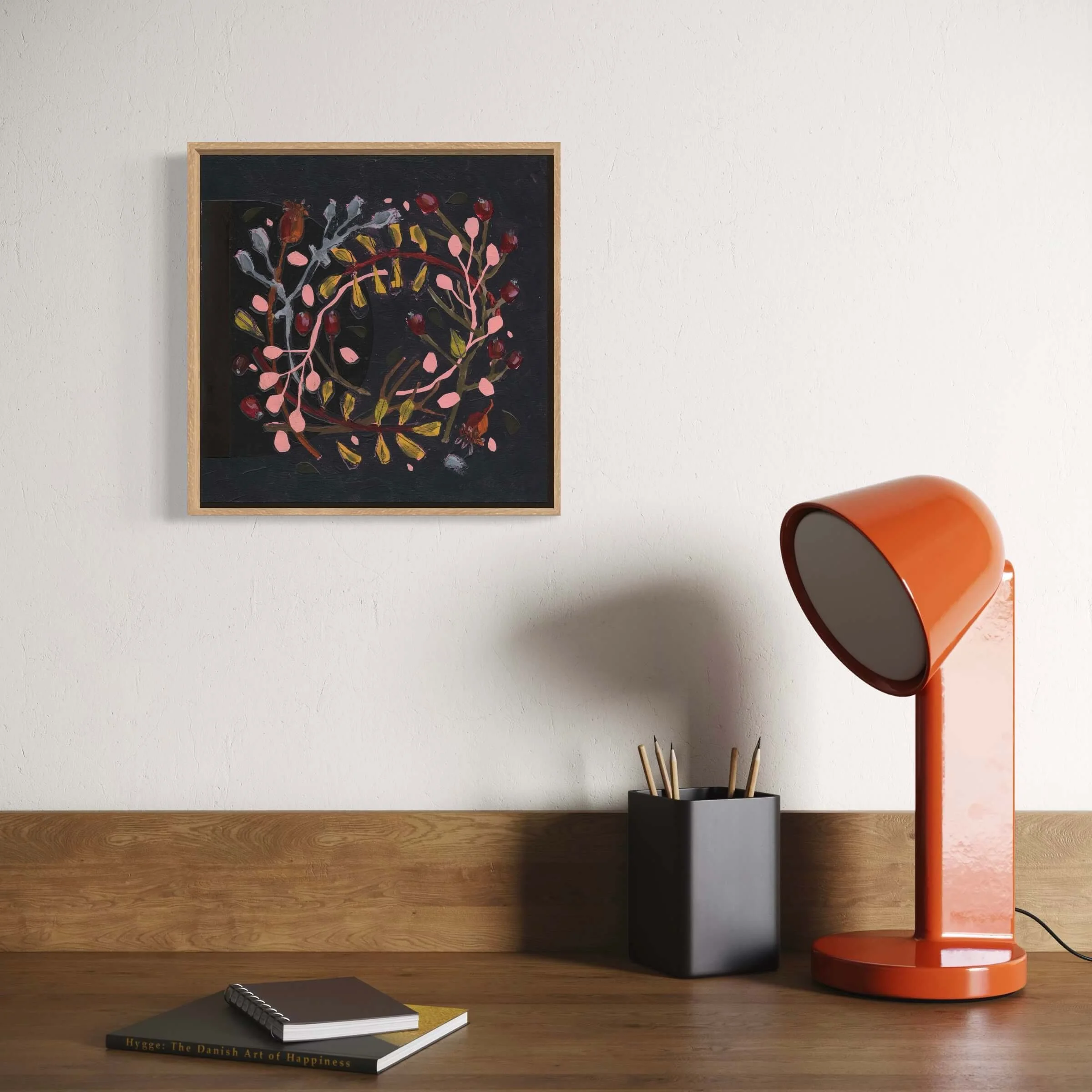 Wallis original botanical painting styled on a warm wooden desk next to a modern orange desk lamp.