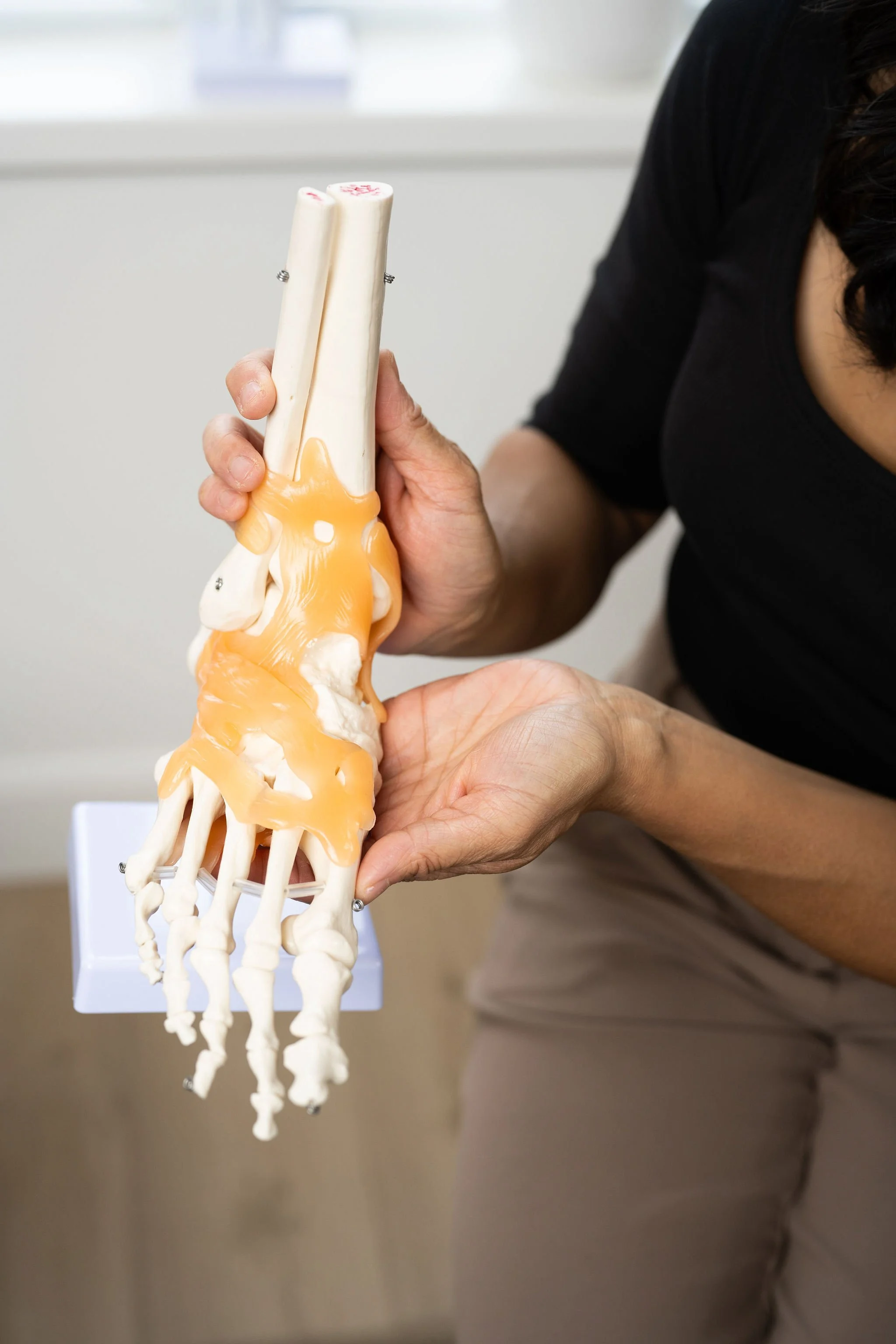 Physiotherapist holding a foot and ankle model to explain custom orthotics