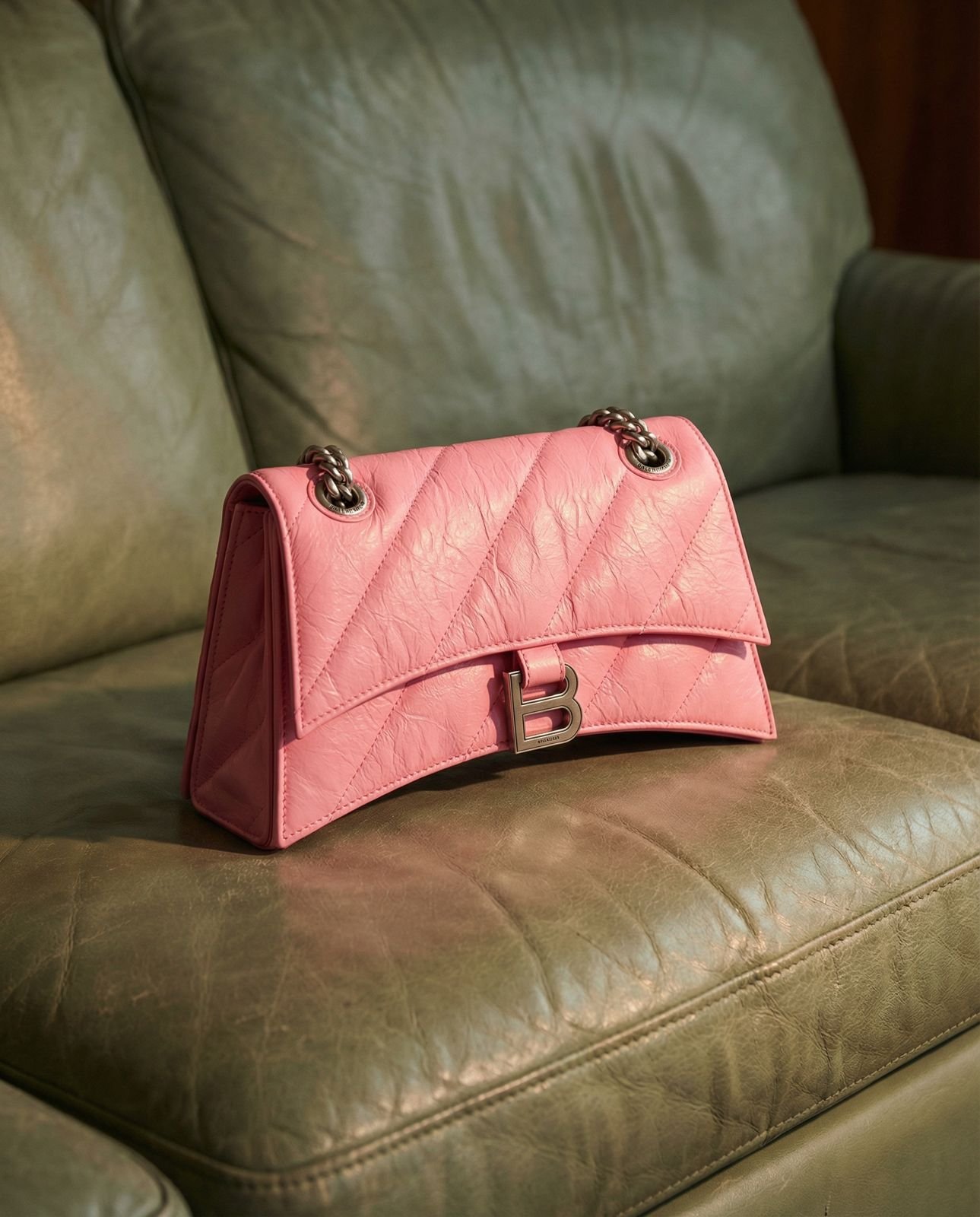 Eine pinke Ledertasche mit silbernem Schnallenverschluss auf einem braunen Ledersofa