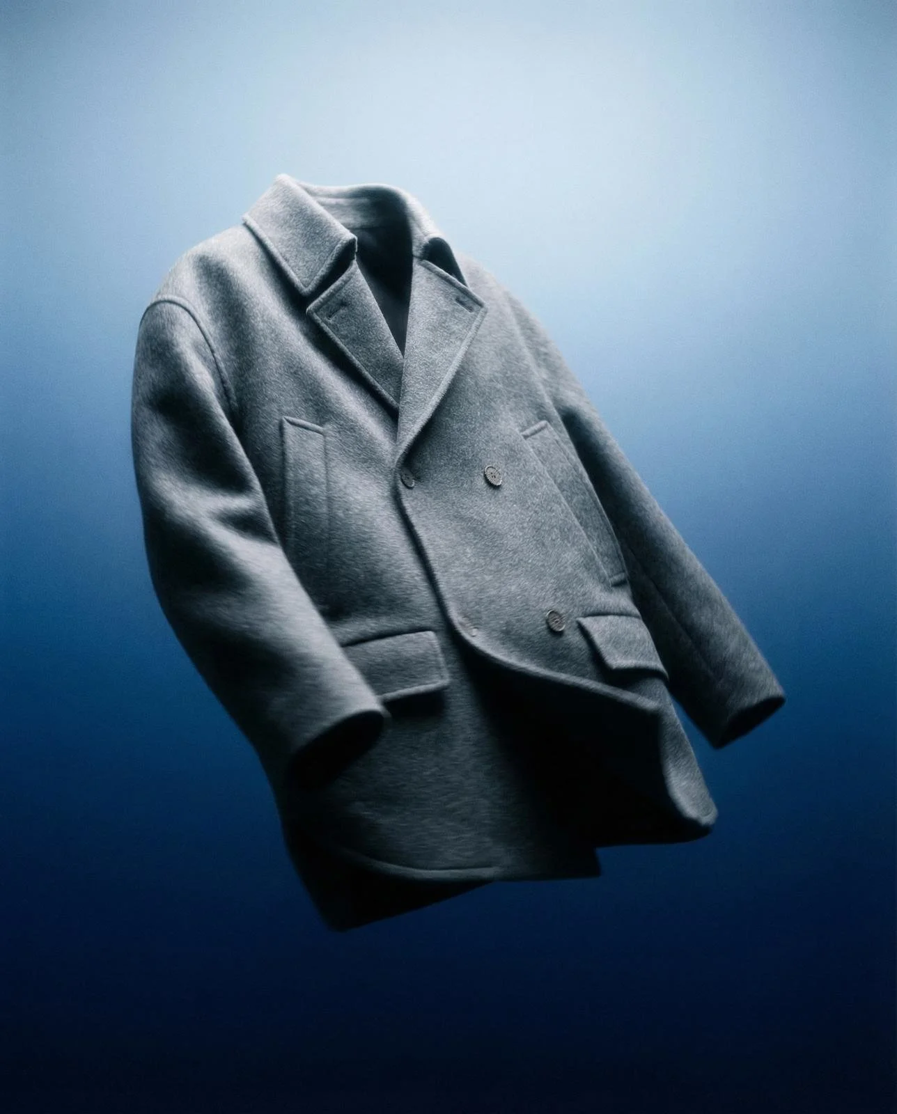 Grauer Wollmantel vor blauem Hintergrund.