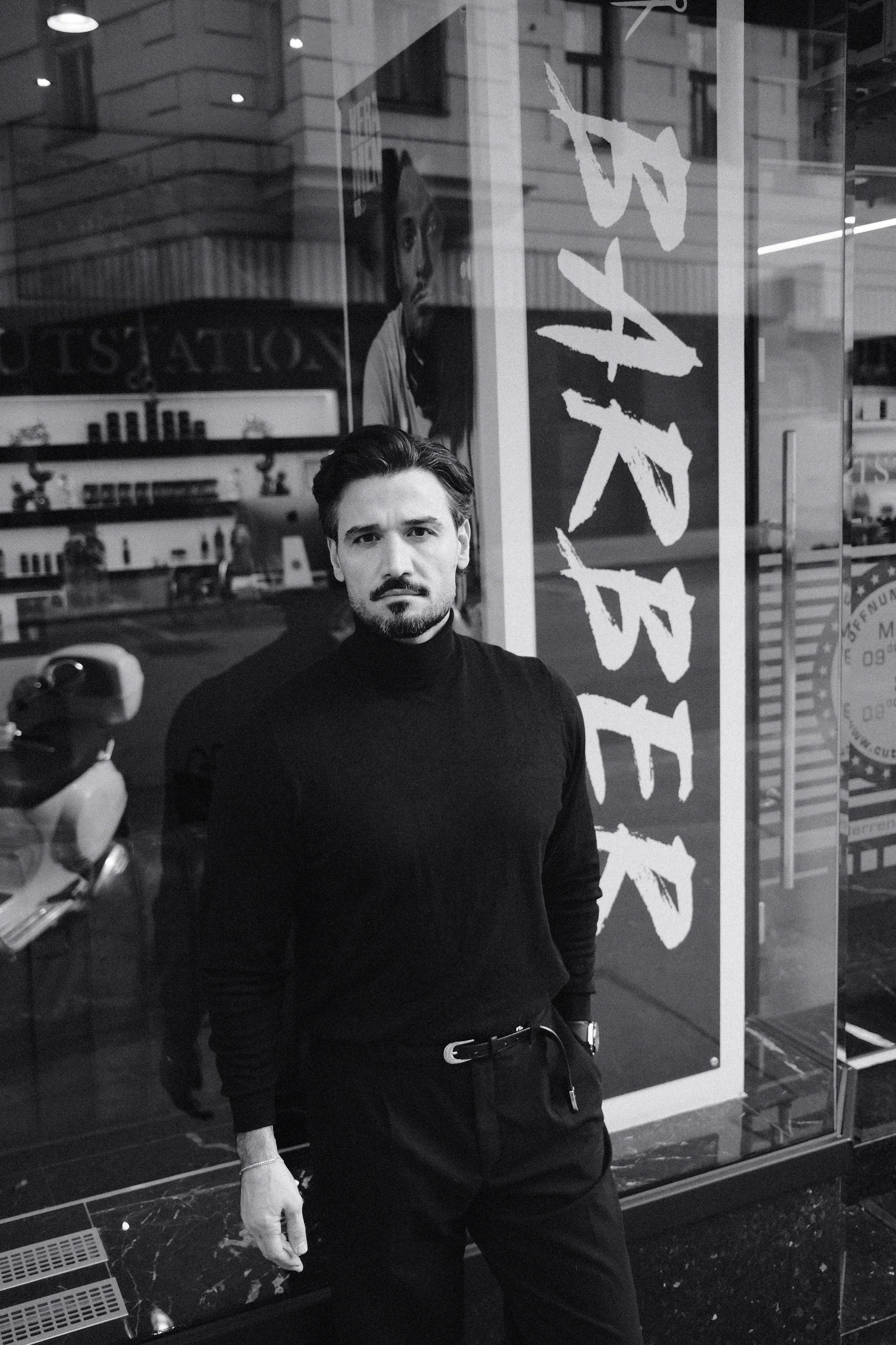 Schwarzer Mann steht vor einem Schaufenster, das das Wort 'VANESSA' zeigt, im Schwarzweißbild.