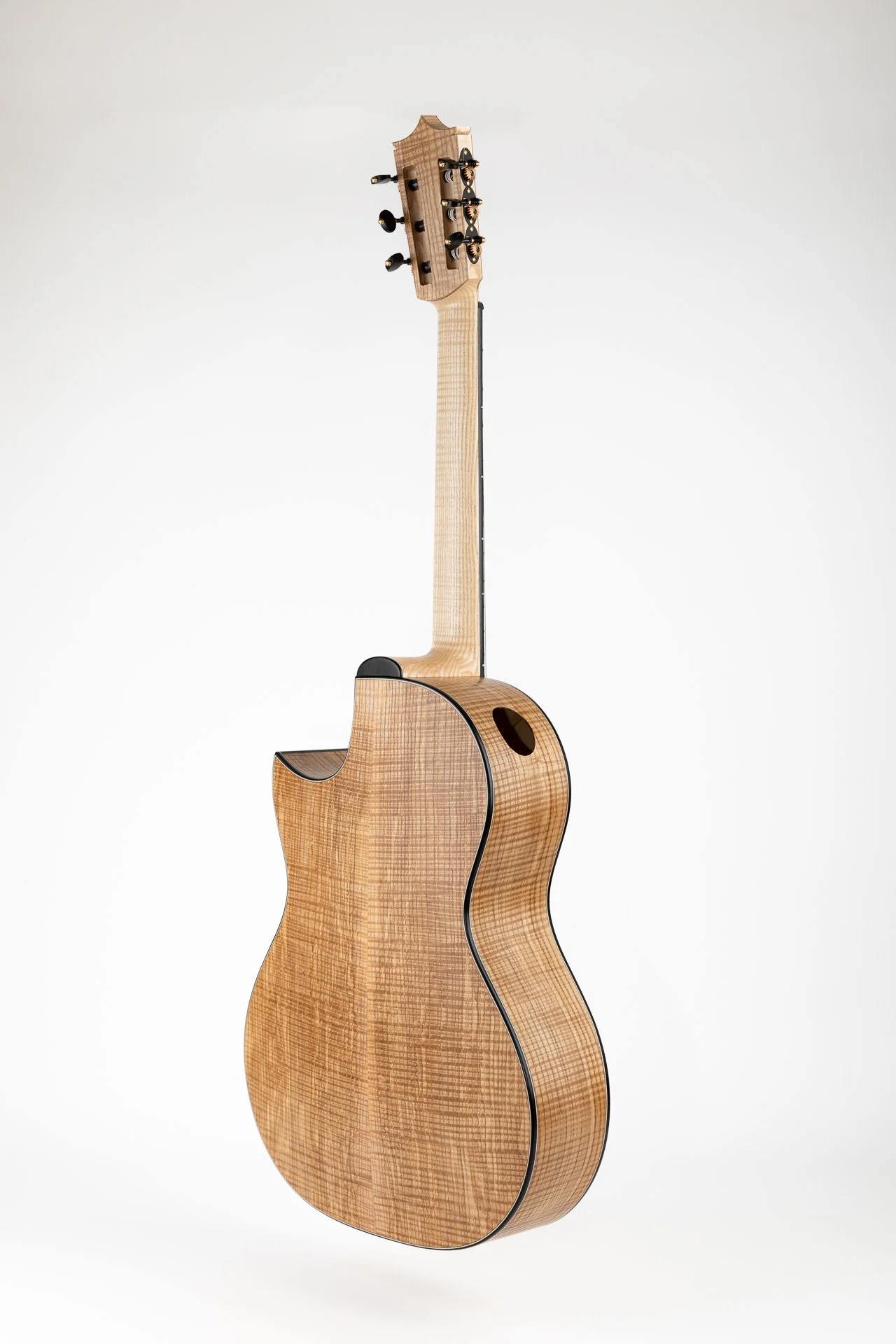 Eine kleine akustische Gitarre aus hellem Holz vor einem weißen Hintergrund.