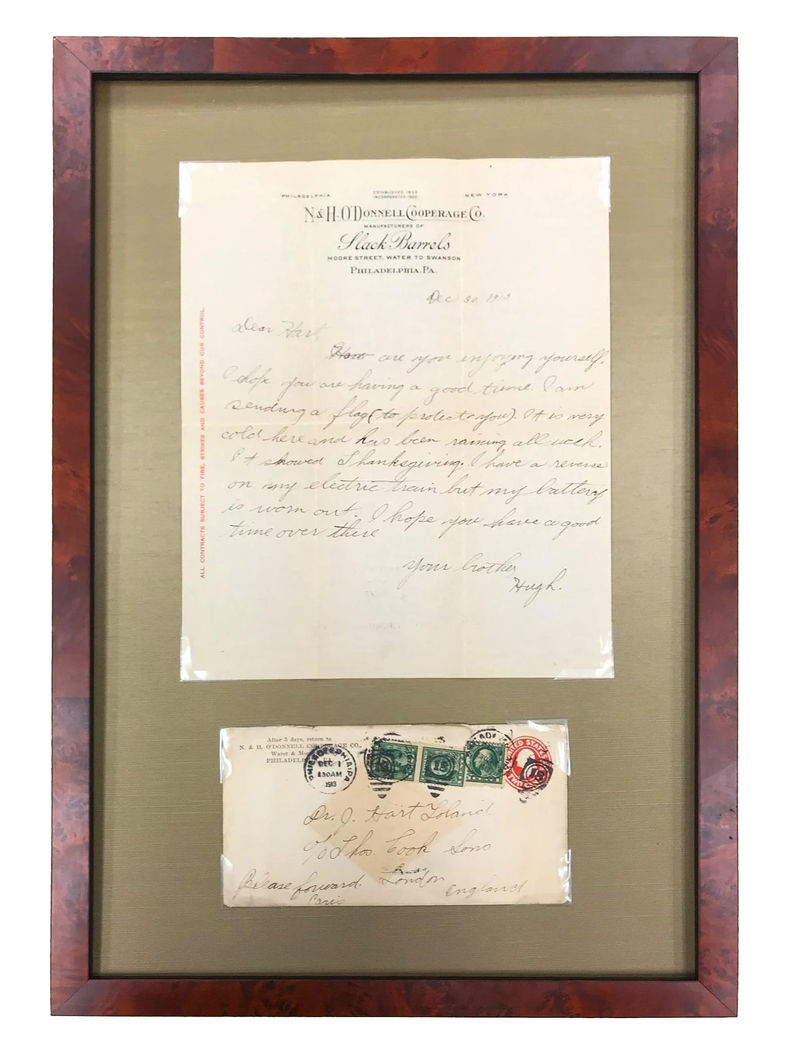 A framed collection of vintage handwritten letters and envelopes, with three green postage stamps and red postage mark, displayed on a gray mat with a wood frame.