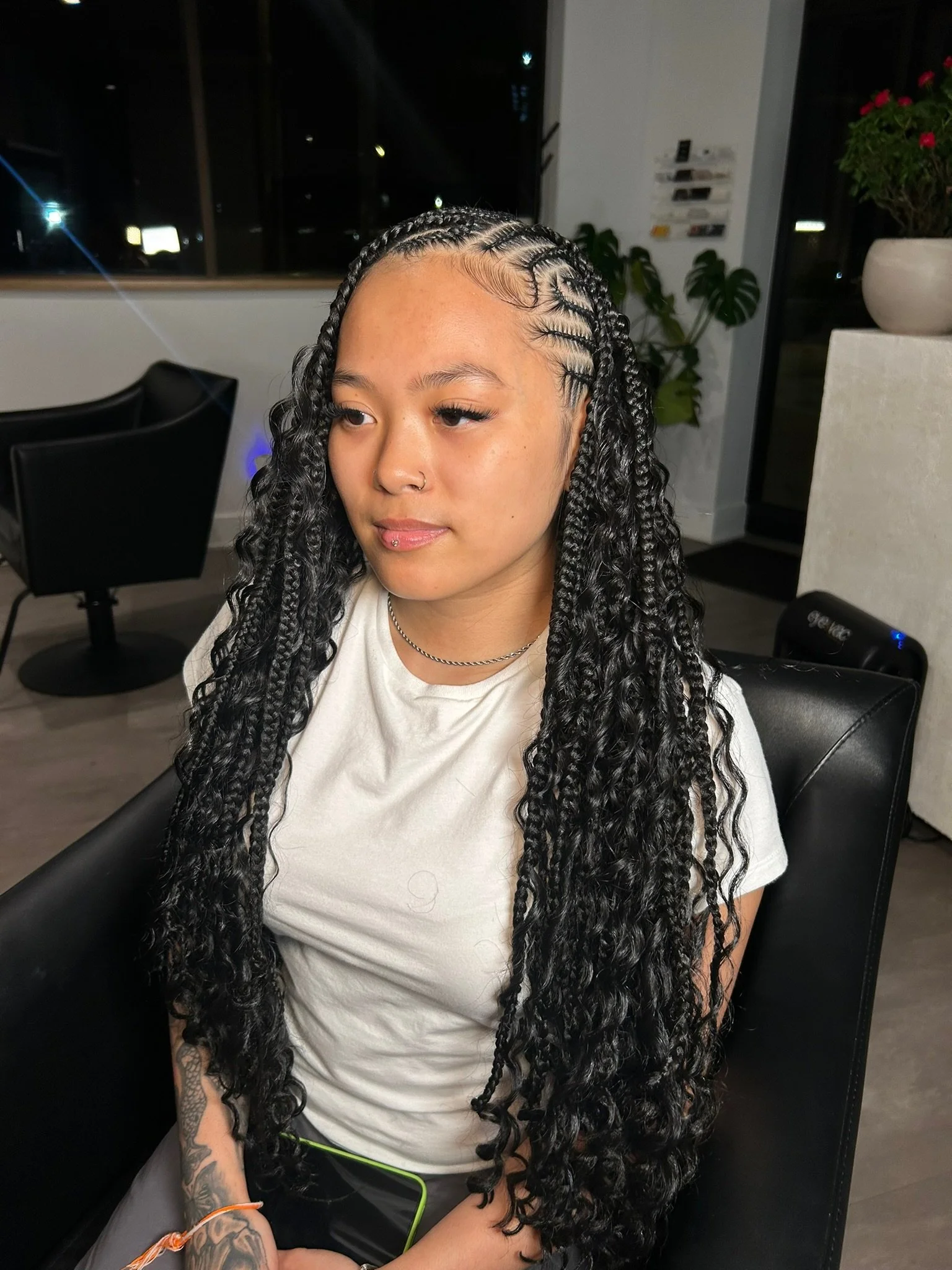 Client with long dark braids and loose curls, photographed from the front in a salon chair.