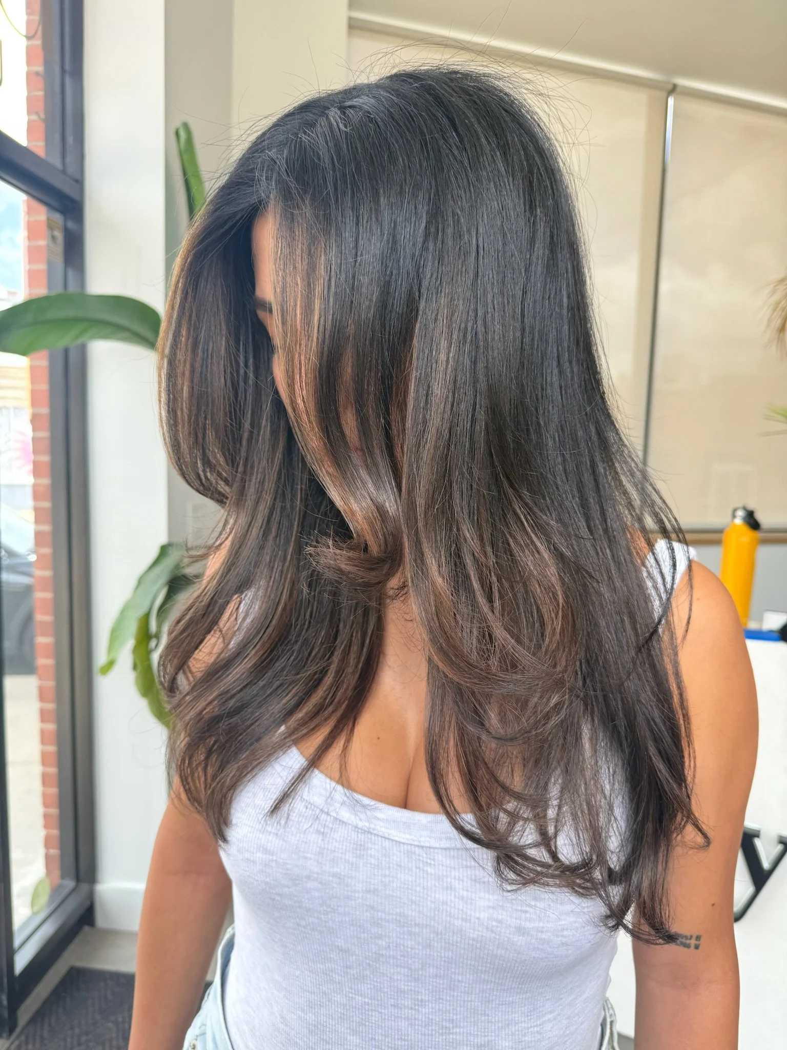 Dark brown layered hair with subtle lighter brown pieces around the face and ends.