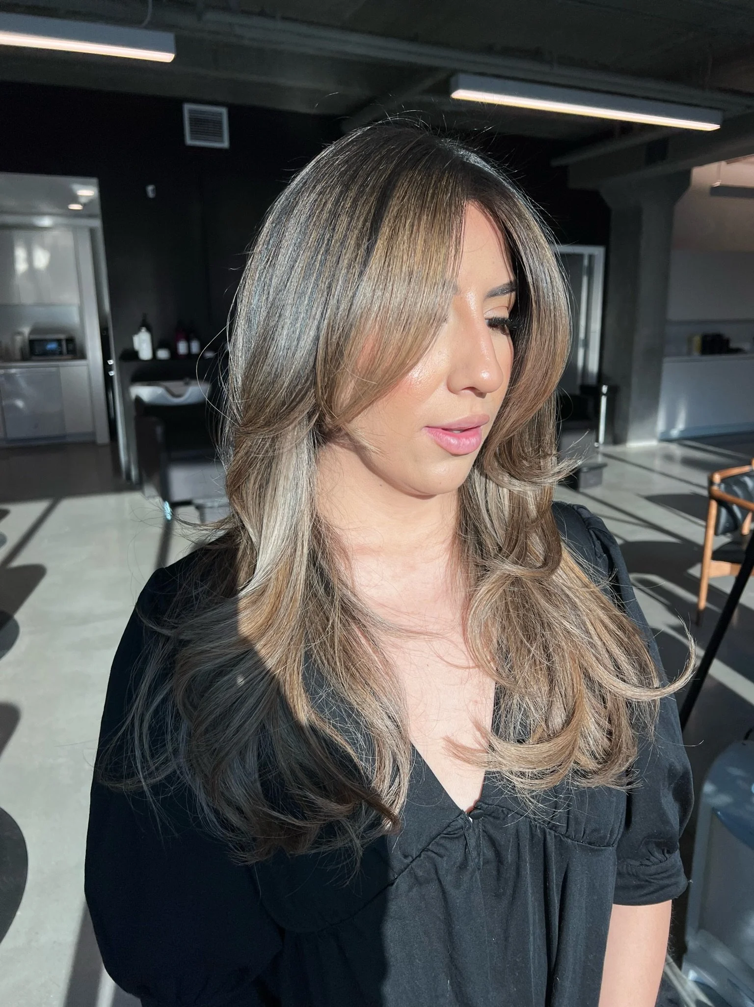 Layered brown and blonde hair with deeper roots and soft face-framing pieces.