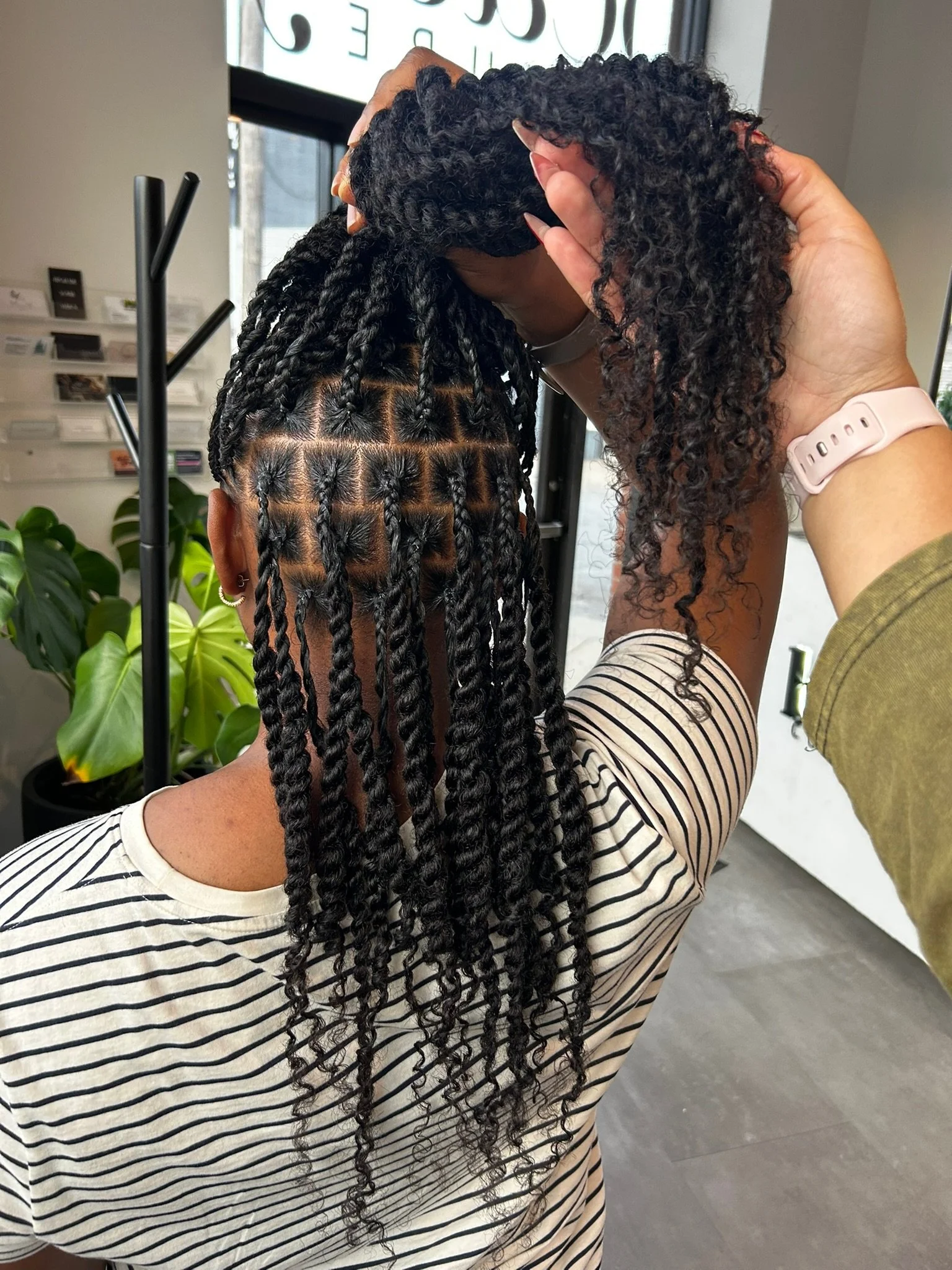 Parted sections and long dark twists viewed from behind in the salon.