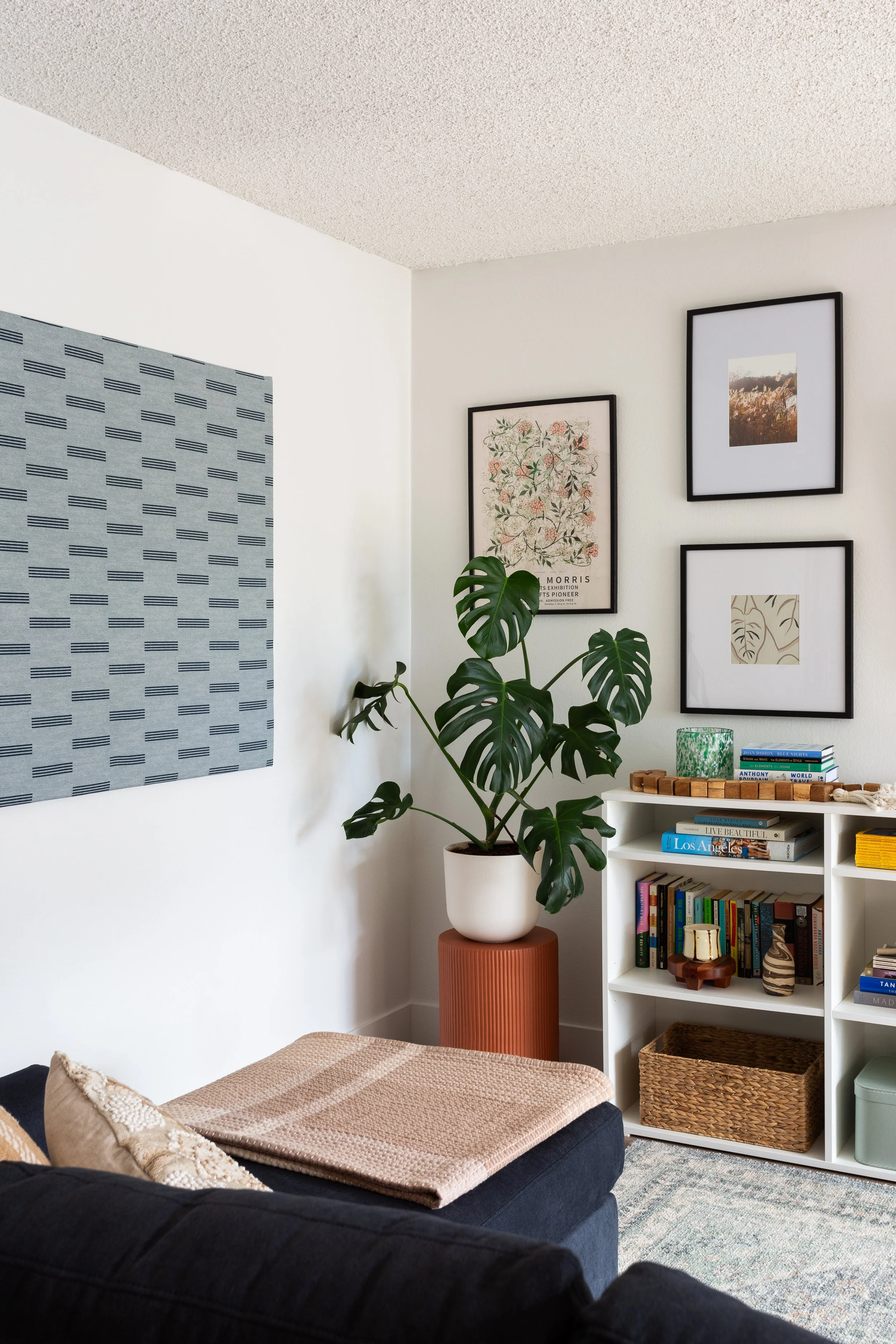 A living room with a blue sofa and a gallery wall above a console table.