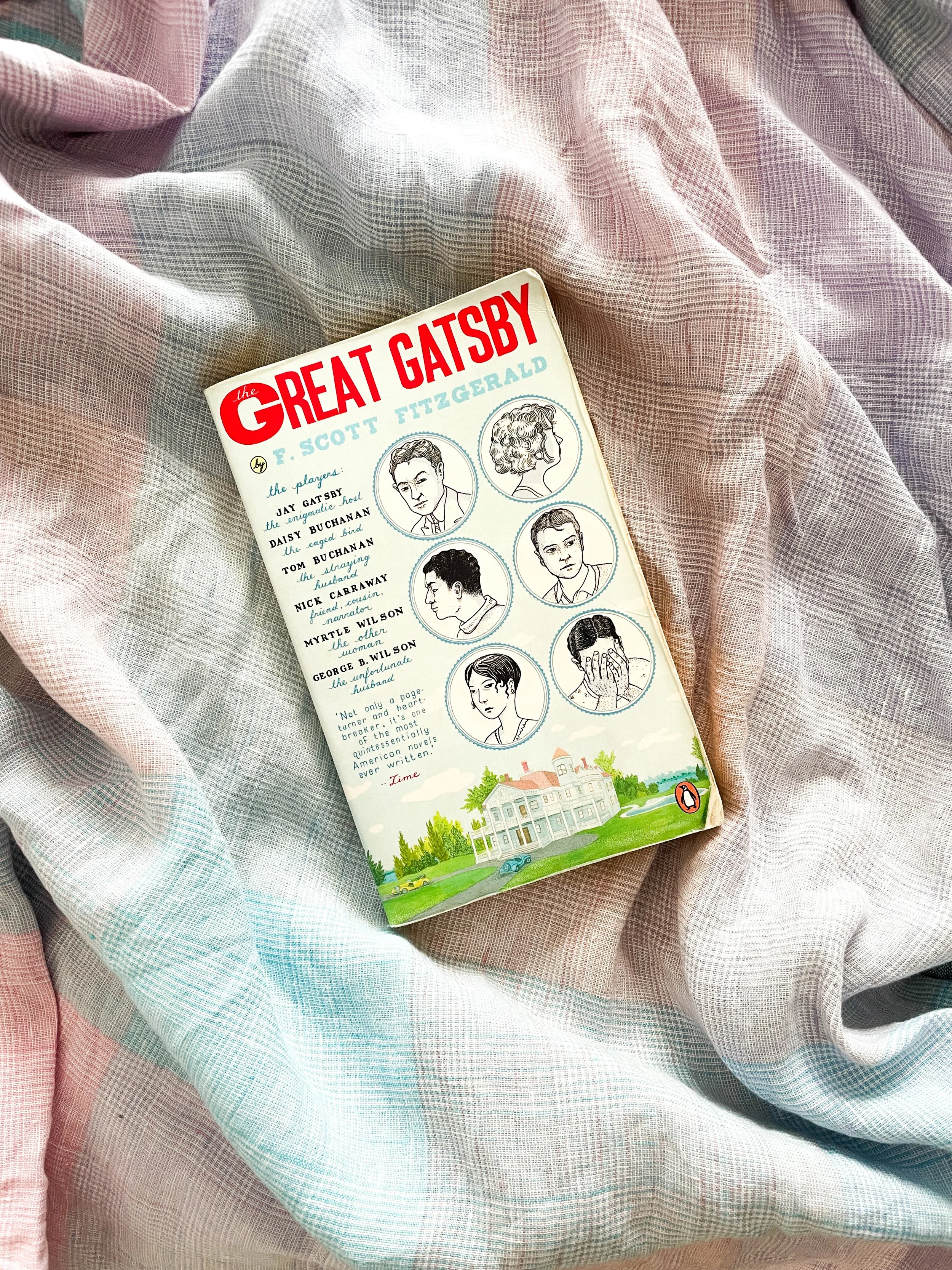 A paperback copy of The Great Gatsby on a plaid shirt.