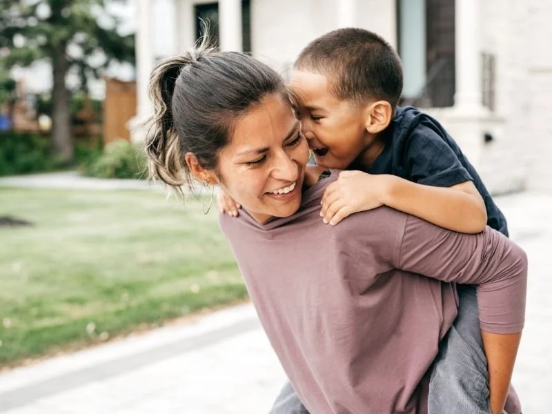 A mom smiling playing with her son after she took care of her parental burnout