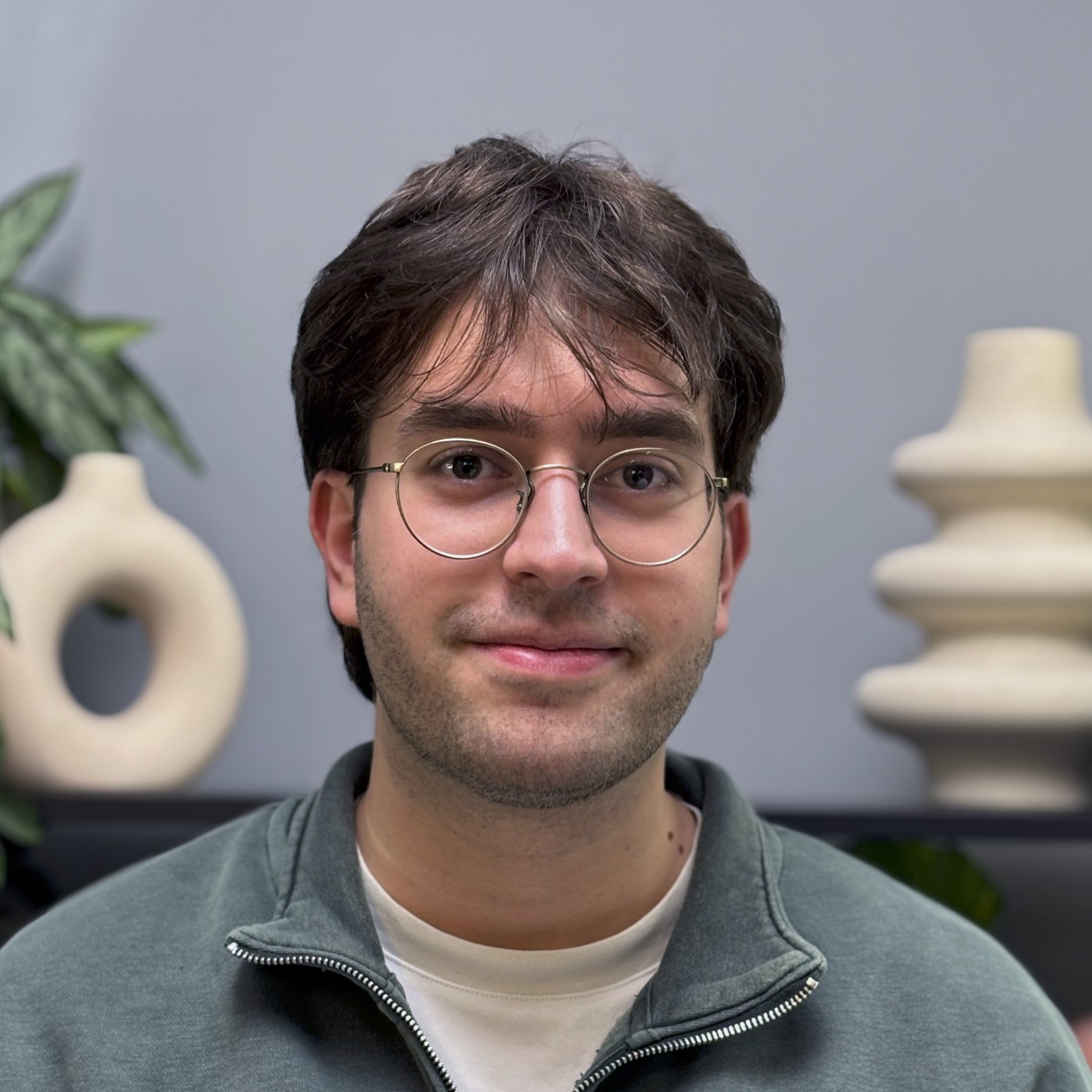 Jamie has wavy brown hair, and is wearing a black tuxedo.