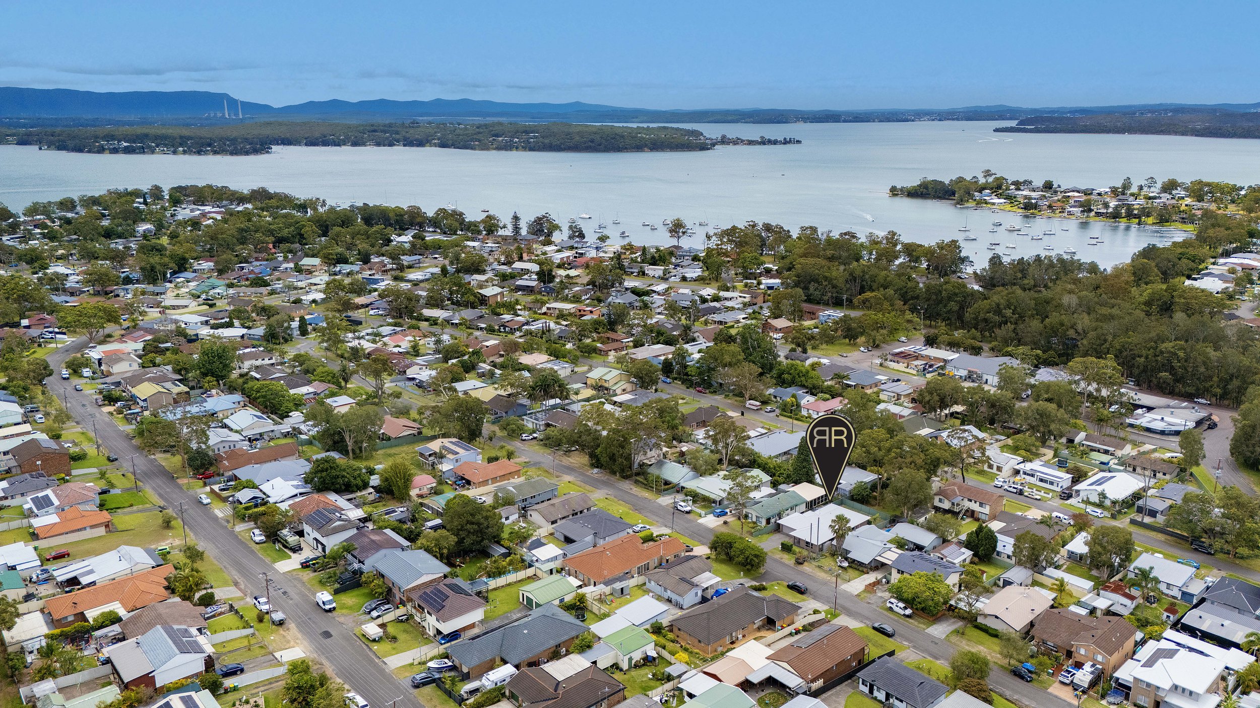 Aerial view of a residential neighborhood near a body of water with boats and islands in the background.