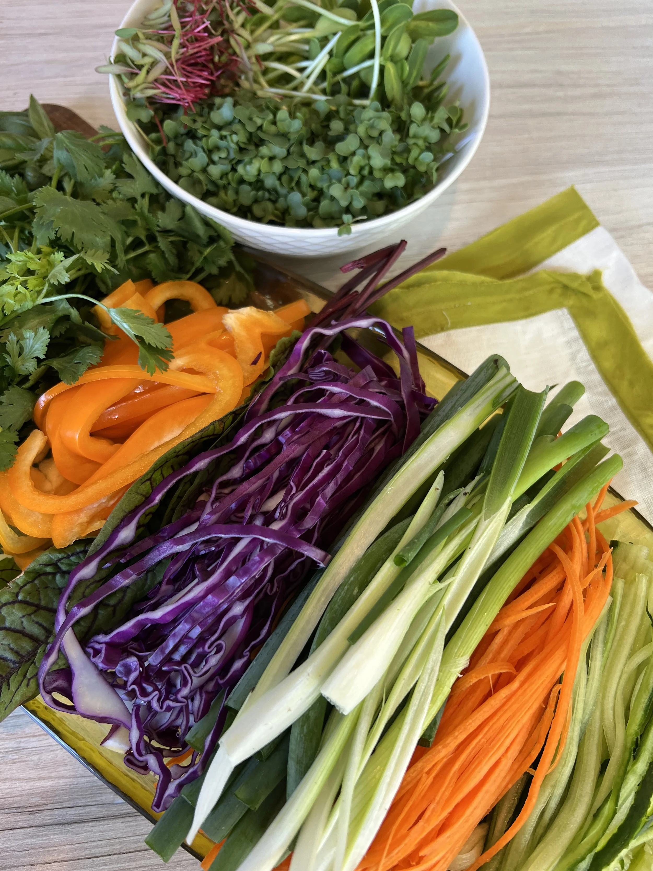 Colorful vegetables, greens and microgreens prepared for raw vegan sushi rolls.