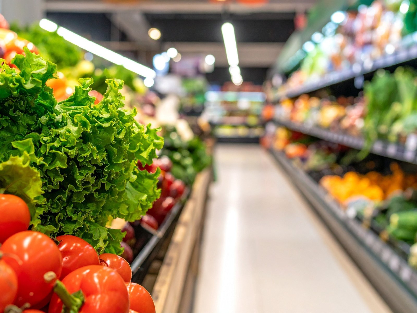 Fresh leafy greens and tomatoes in a grocery store produce isle