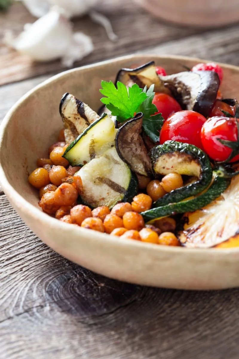 Plant-based bowl with chickpeas, roasted zucchini,  tomatoes, and fresh herbs.