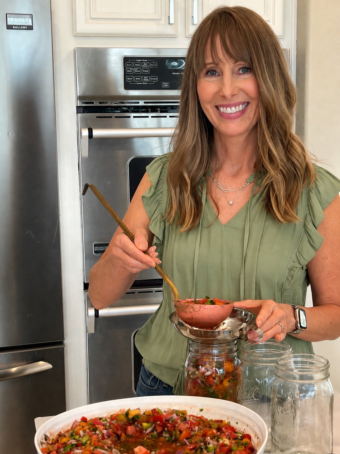 Michelle spooning fresh salsa into wide-mouth Mason jars before fermentation.
