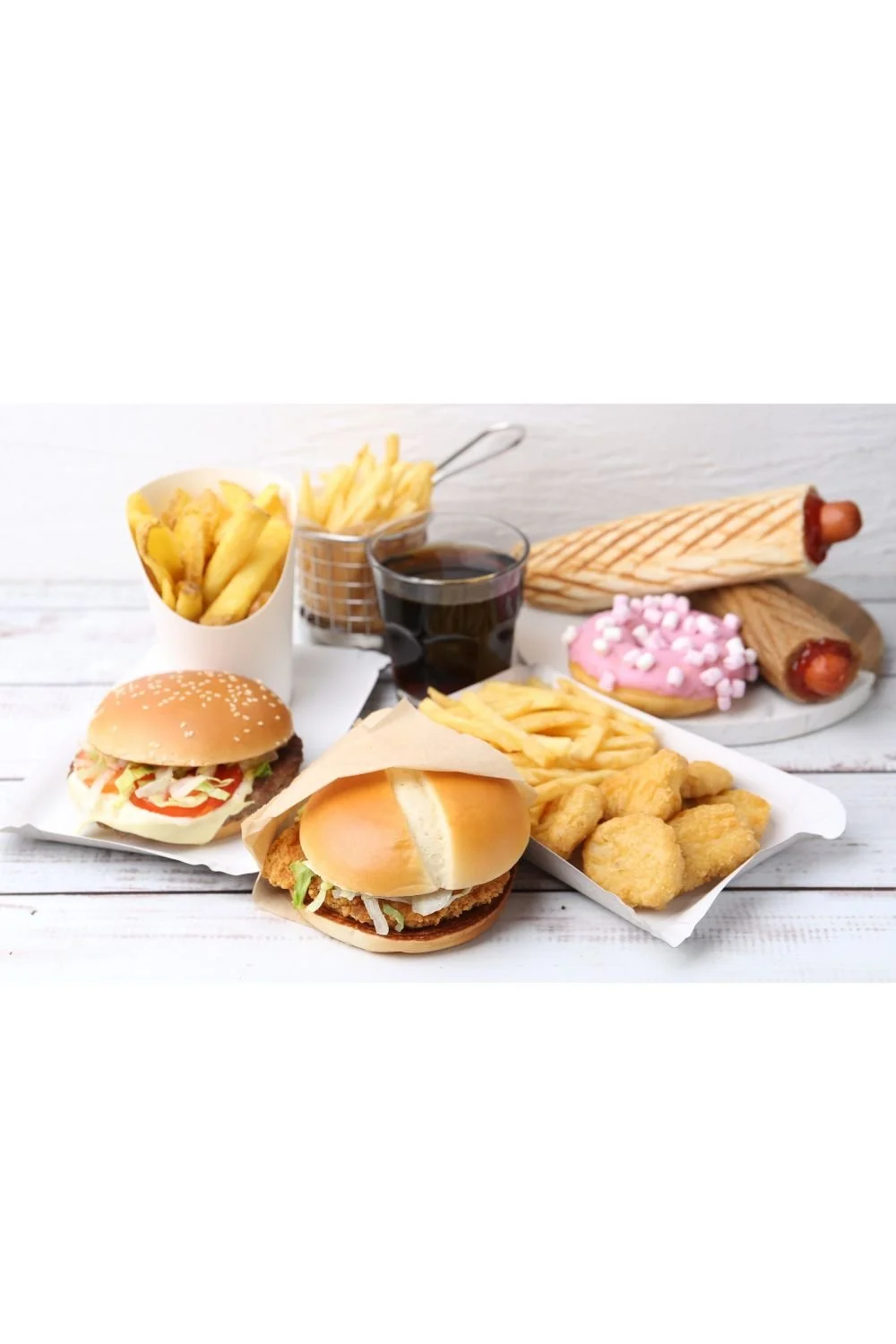 Fast food meal including burgers, fries, soda, hotdogs, and a cookie associated with inflammation and poor gut health