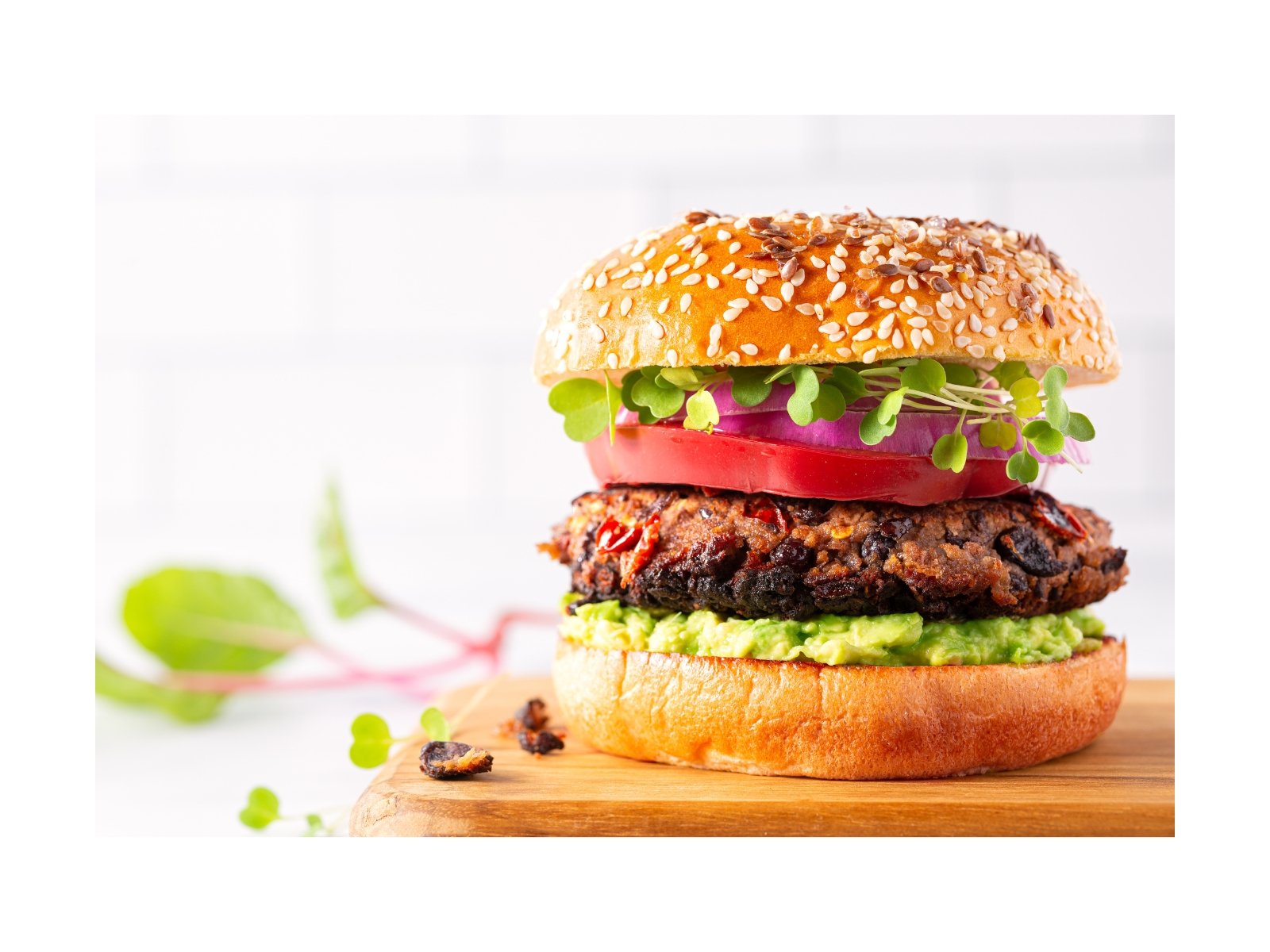 Plant-based burger with avocado, tomato, microgreens, and a sesame bun
