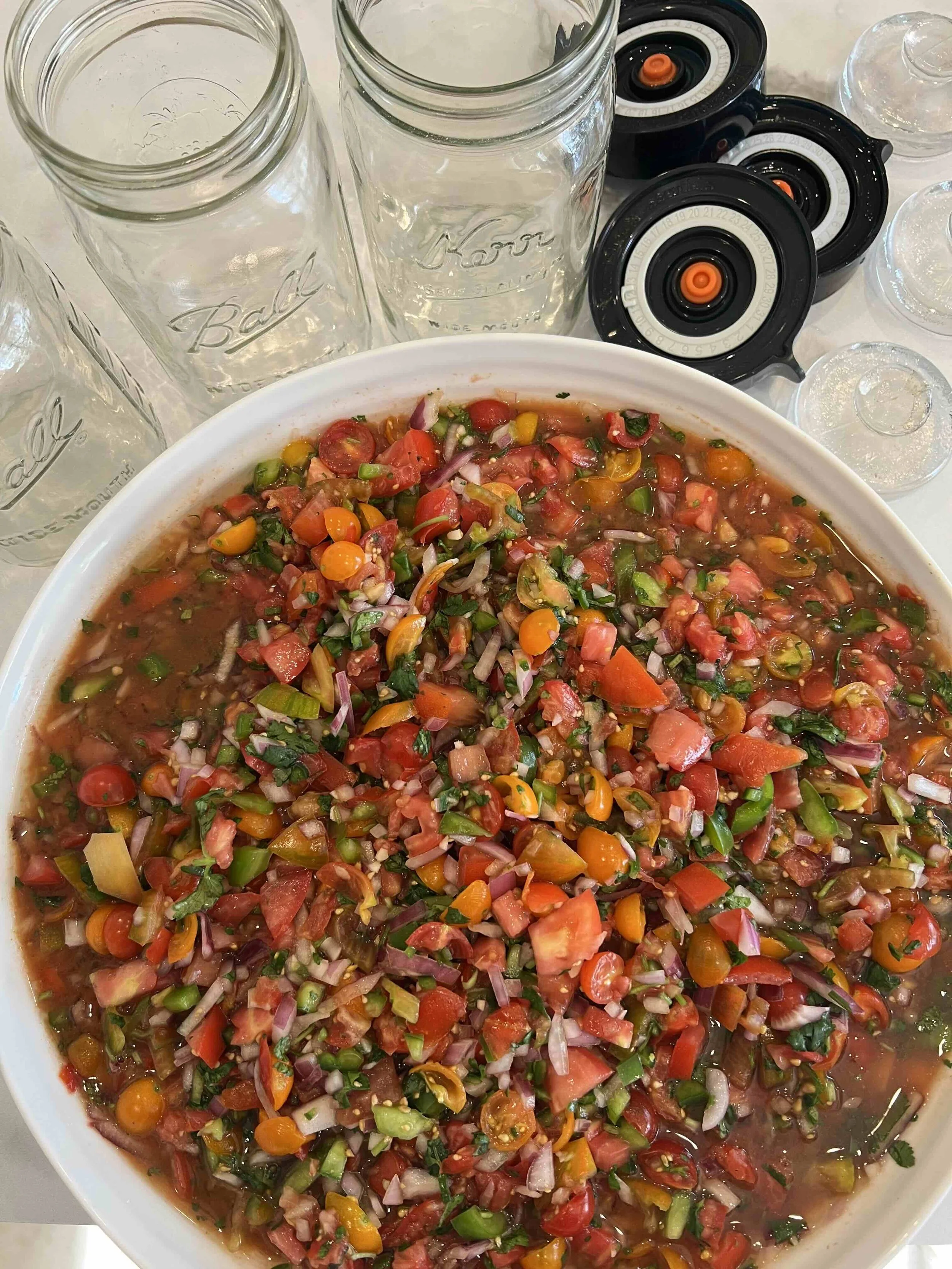 Fresh salsa with wide-mouth Mason jars, fermentation lids and glass weights ready for fermenting.