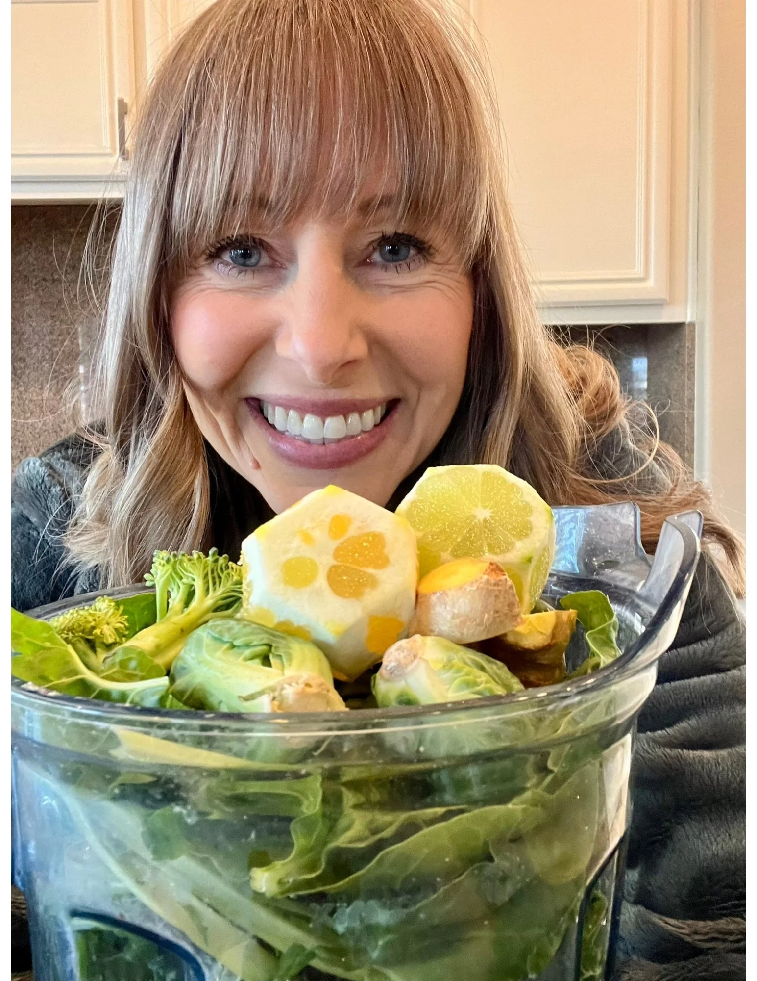 Woman holding a vitamix blender of leafy greens, broccoli, brussels sprouts, spinach and lemon while following Dr. Brooke Goldner's Goodbye Autoimmune Protocol.
