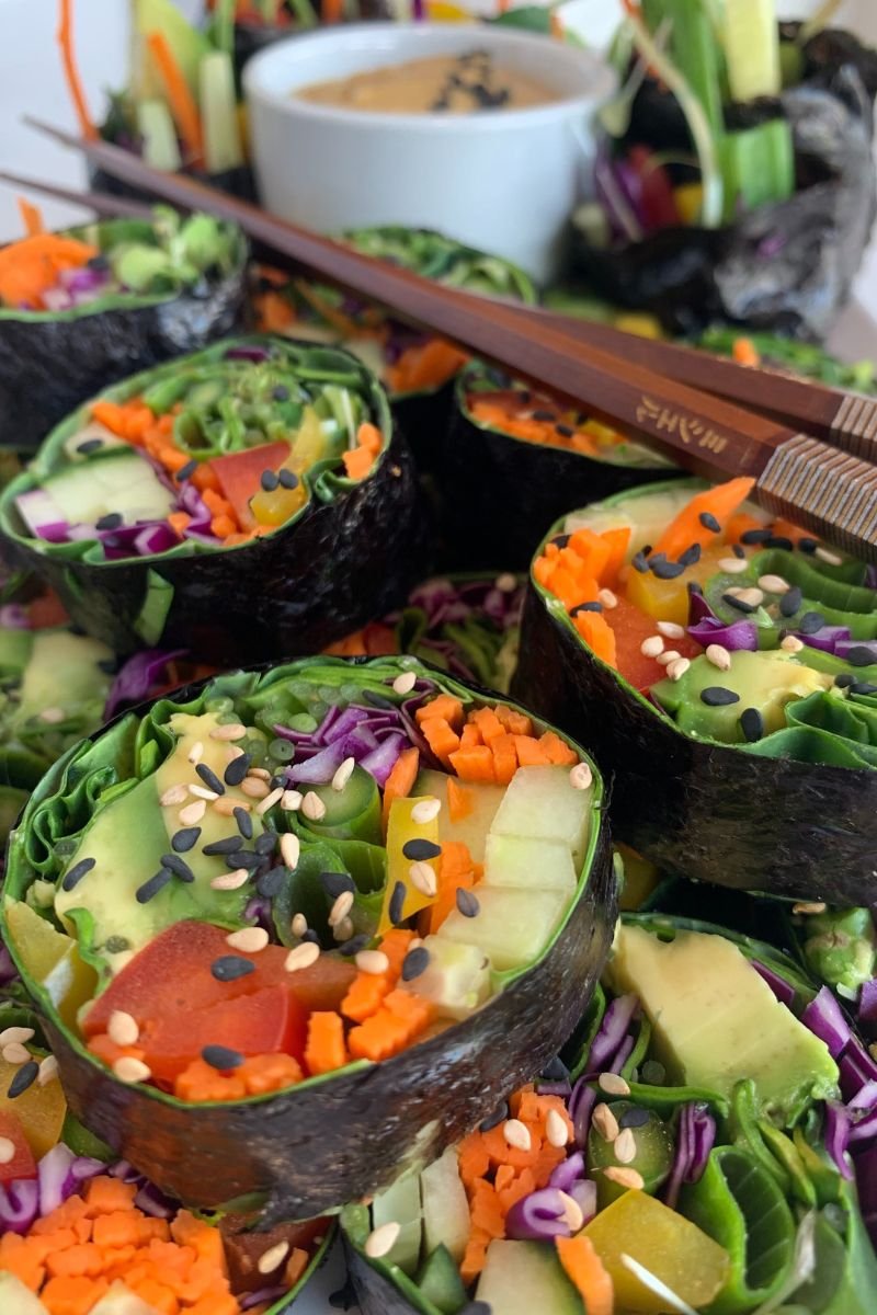 Raw vegan sushi rolls filled with avocado, carrots,cucumber, greens and colorful fresh vegetables.