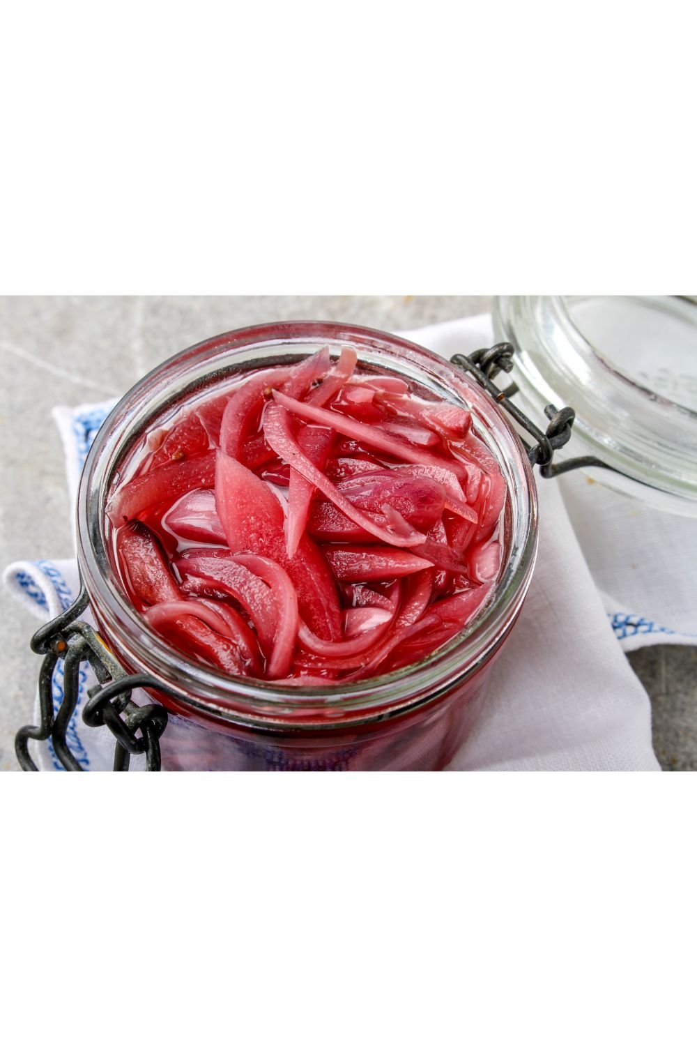 Homemade fermented red onions in a glass jar.